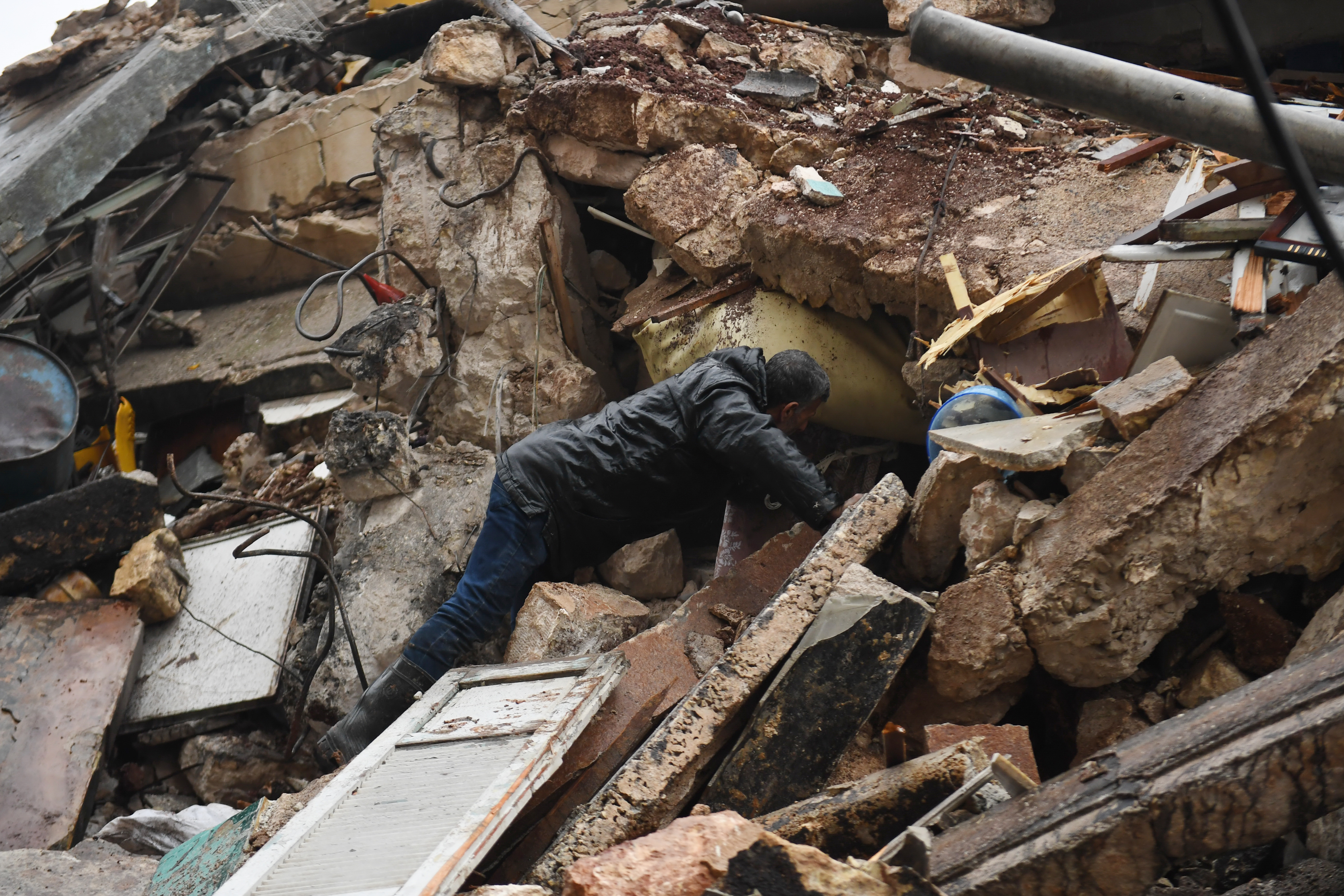 A man looks for survivors under the rubble of a collapsed building after an earthquake in the regime-controlled northern Syrian city of Aleppo on February 6, 2023. A 7.8-magnitude earthquake hit Turkey and Syria early on February 6, killing hundreds of people as they slept, levelling buildings and sending tremors that were felt as far away as the island of Cyprus, Egypt and Iraq.