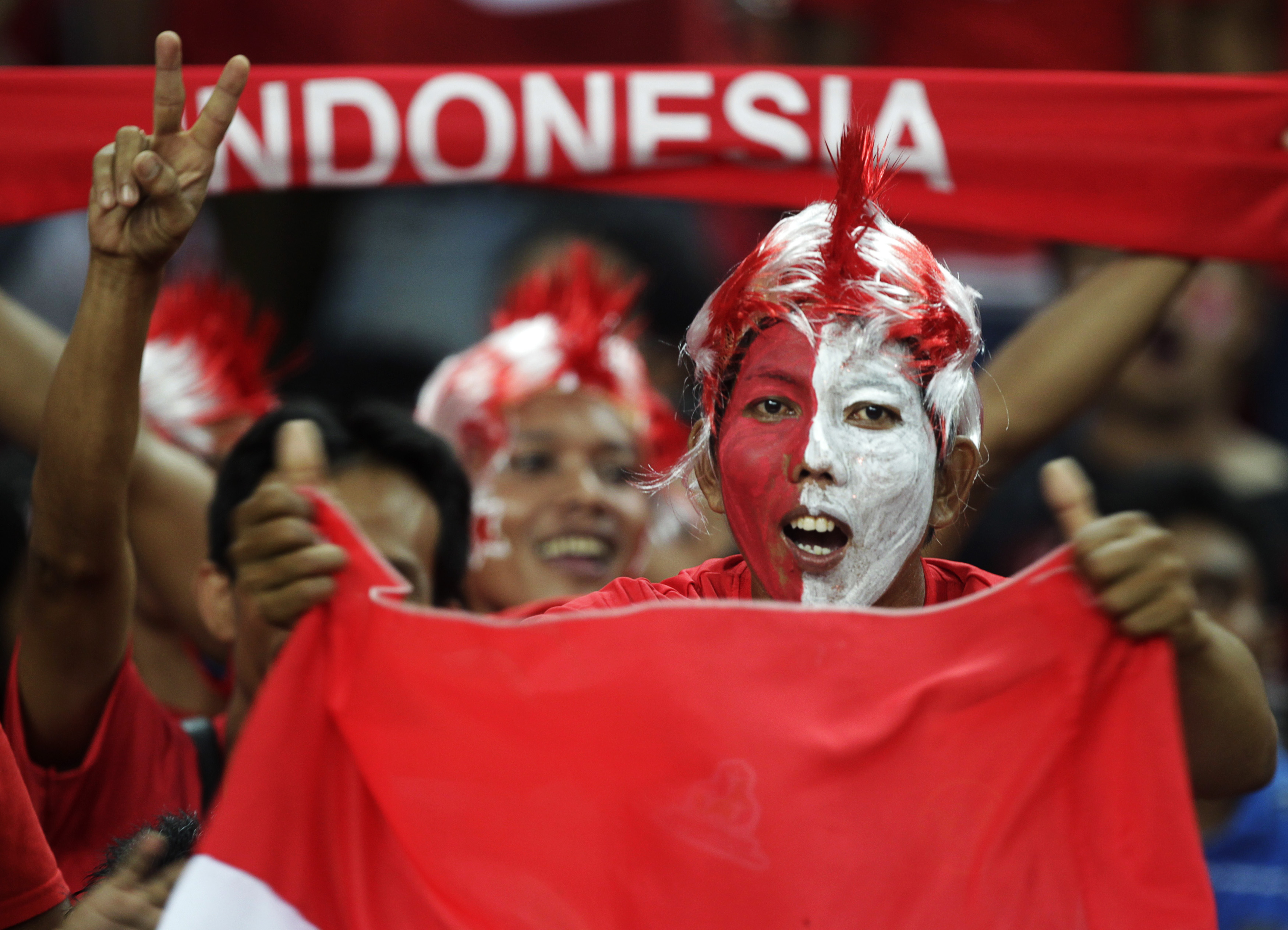 Indonesian fans dressed in national colours cheer as they hold flags and banners before the final first leg match between Indonesia and Malaysia during the ASEAN Football Federation (AFF) Suzuki Cup 2010 soccer tournament in Kuala Lumpur December 26, 2010. REUTERS/Bazuki Muhammad (KUALA LUMPUR - Tags: SPORT SOCCER)