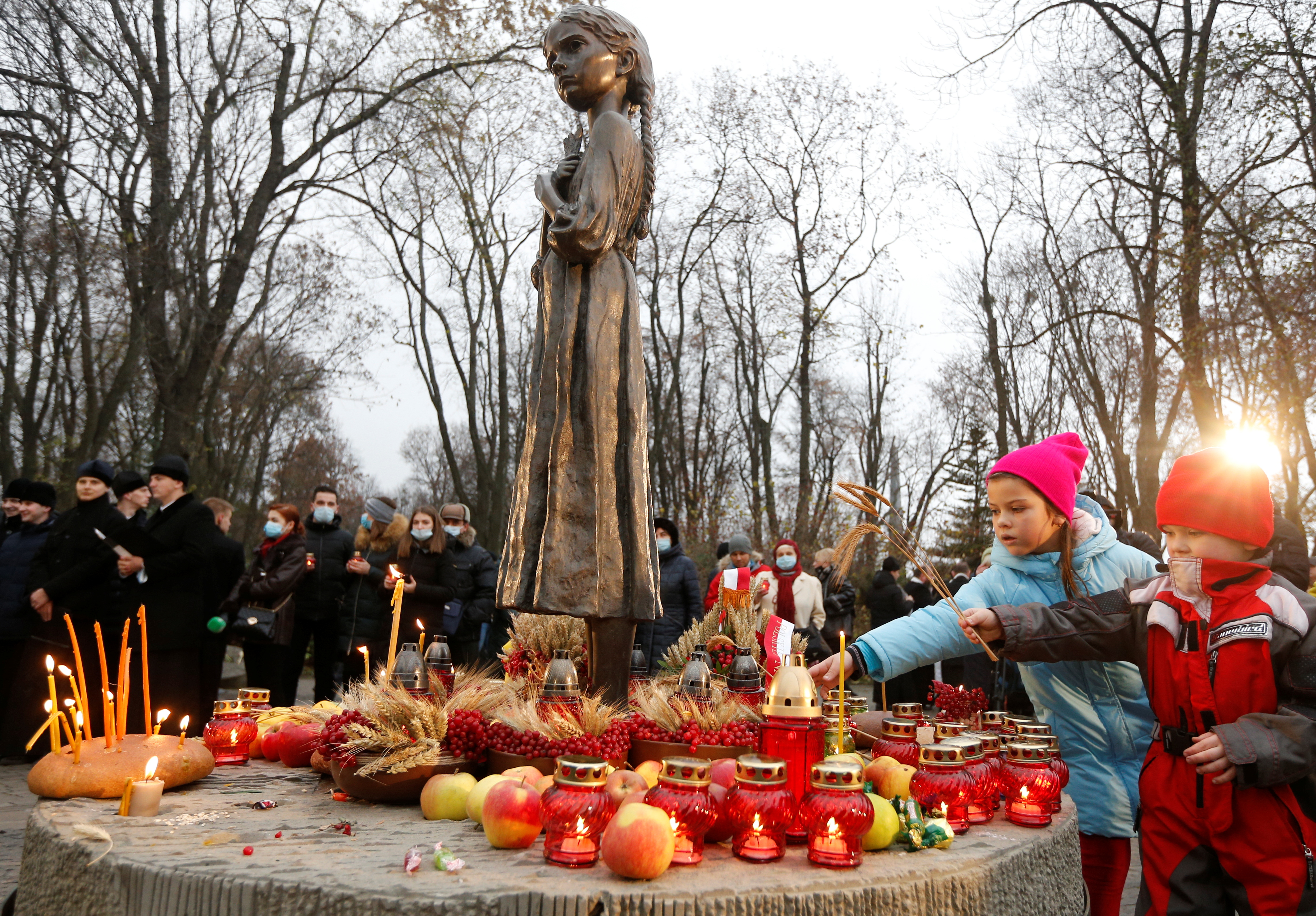 Children place ears of wheat as they visit a monument to Holodomor victims during a commemoration ceremony marking the 87th anniversary of the famine of 1932-33, in which millions died of hunger, in Kyiv, Ukraine, November 28, 2020.