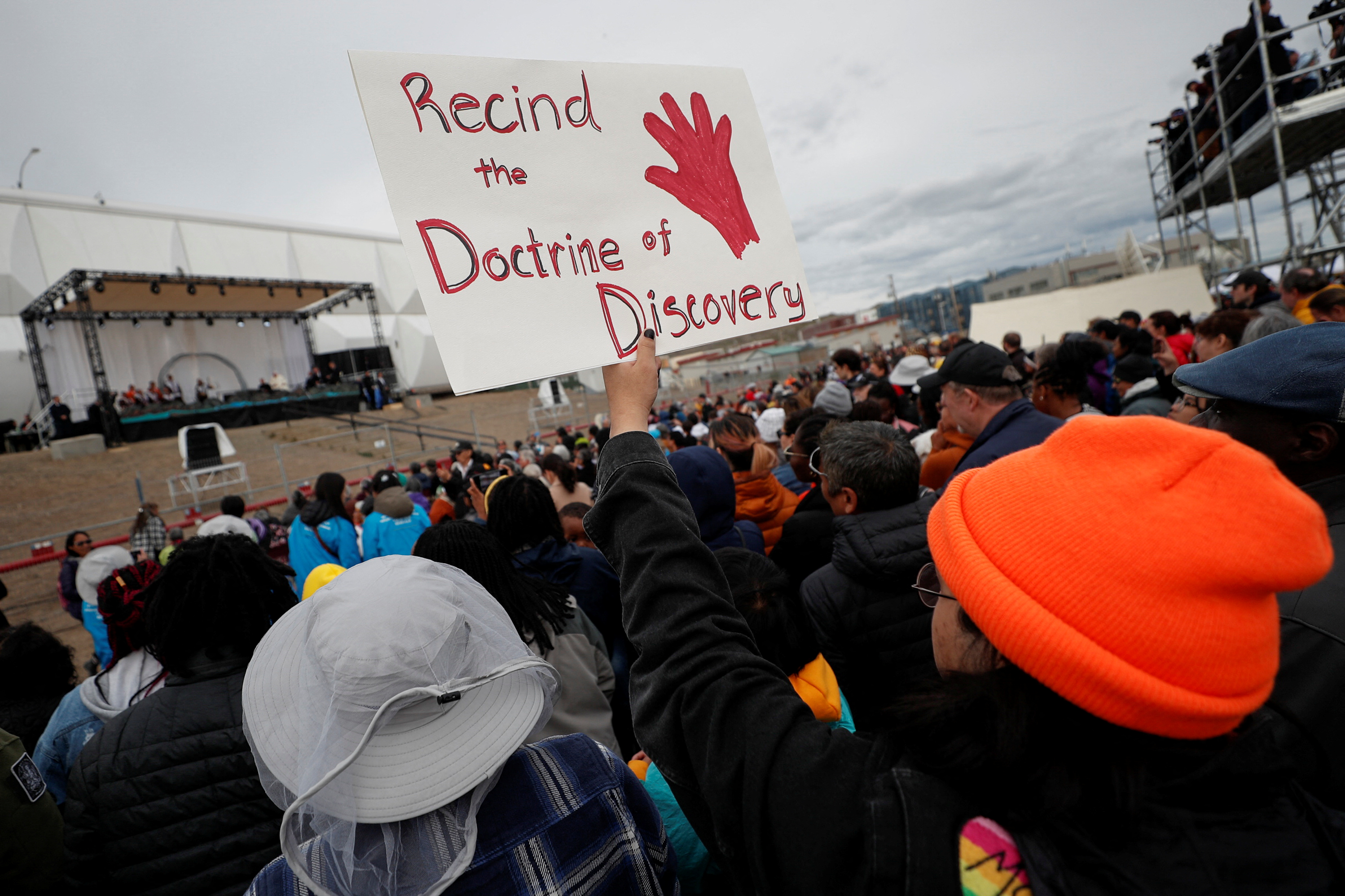 A person holds a sign reading 'Rescind the Doctrine of Discovery' during a visit by Pope Francis to Nunavut, Canada