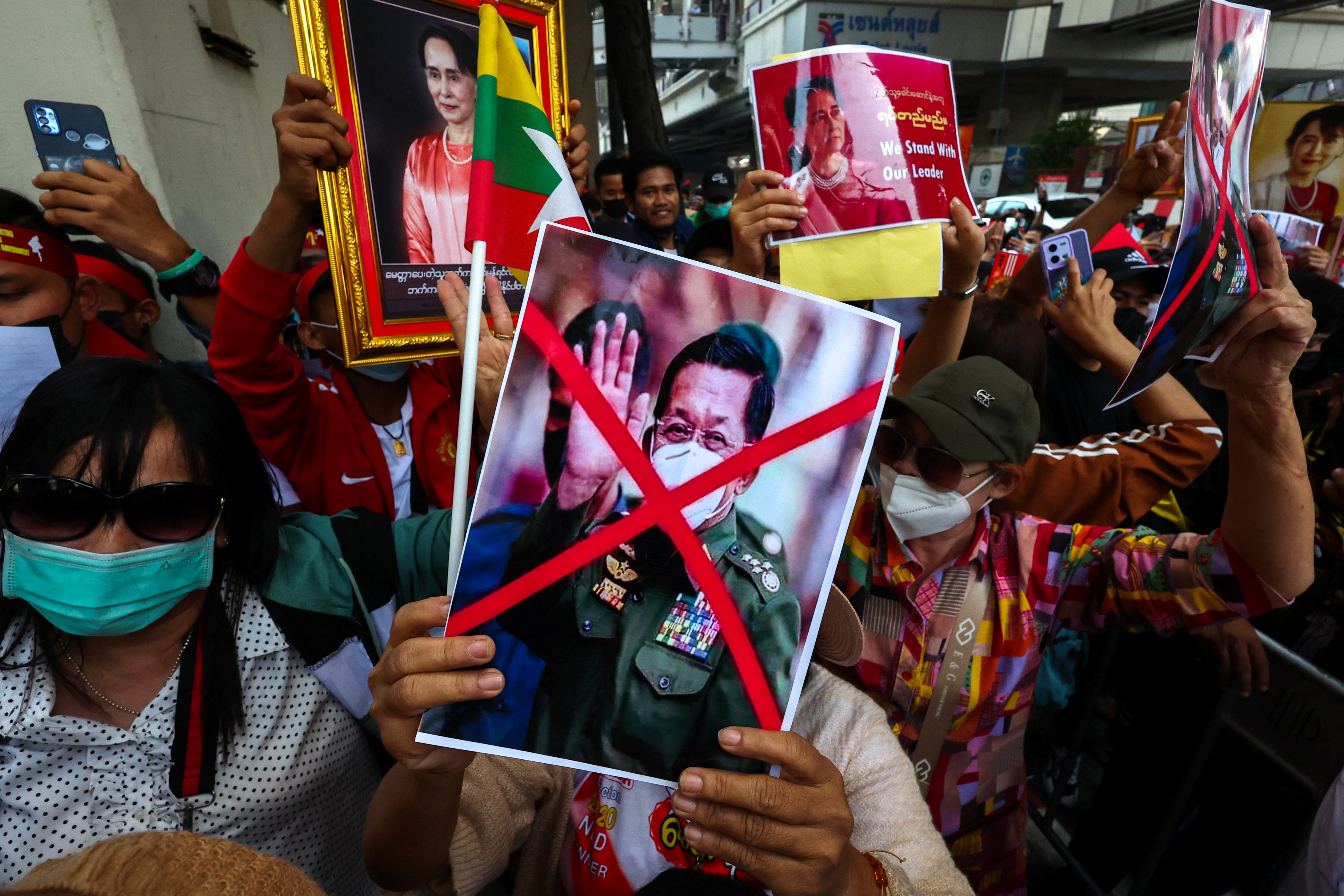 A protester holding a picture of Min Aung Hlaing with a red cross across it. There are other protesters behind them.