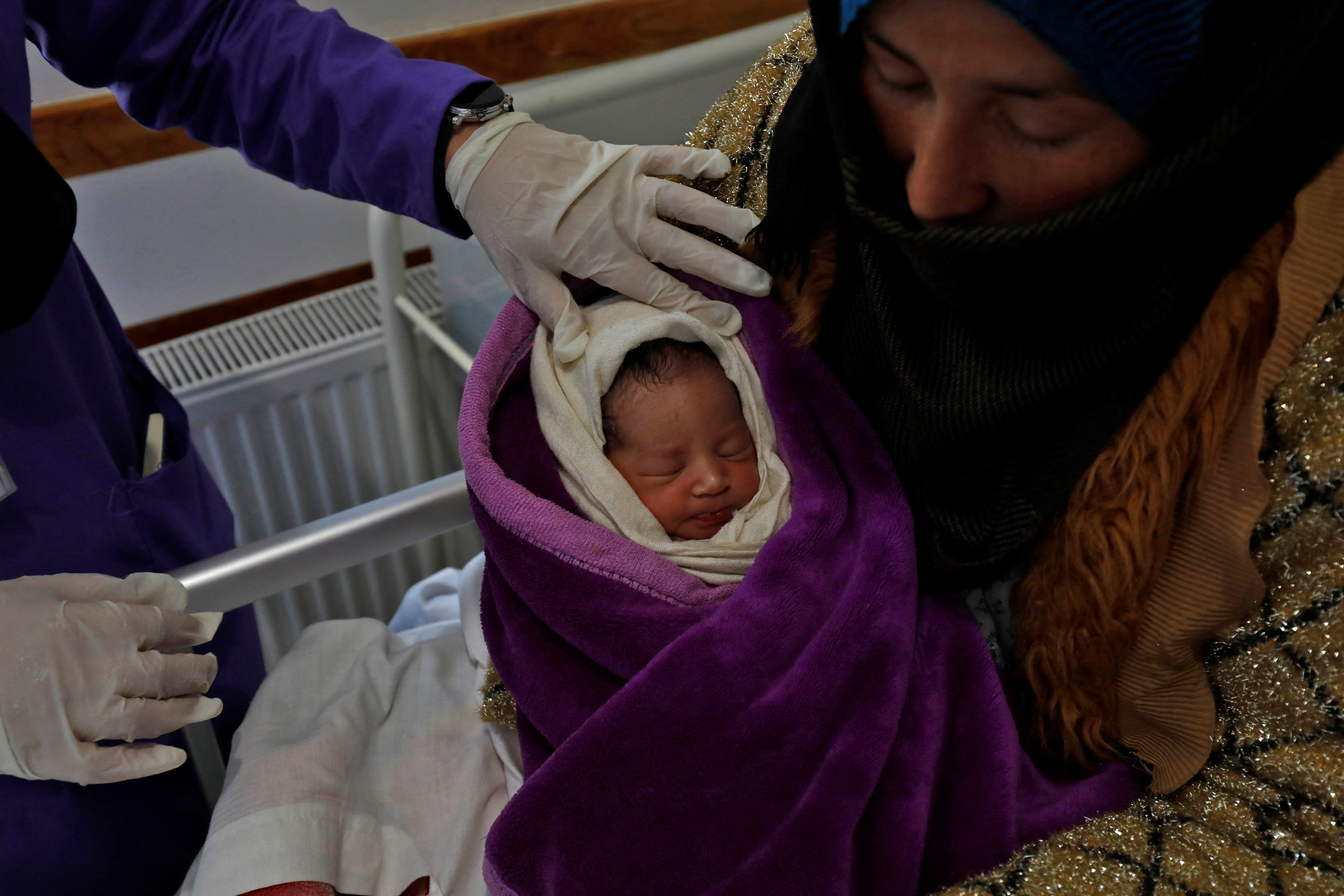 A trainee midwife examines a woman and her newborn baby at a hospital in Bamiyan, Afghanistan