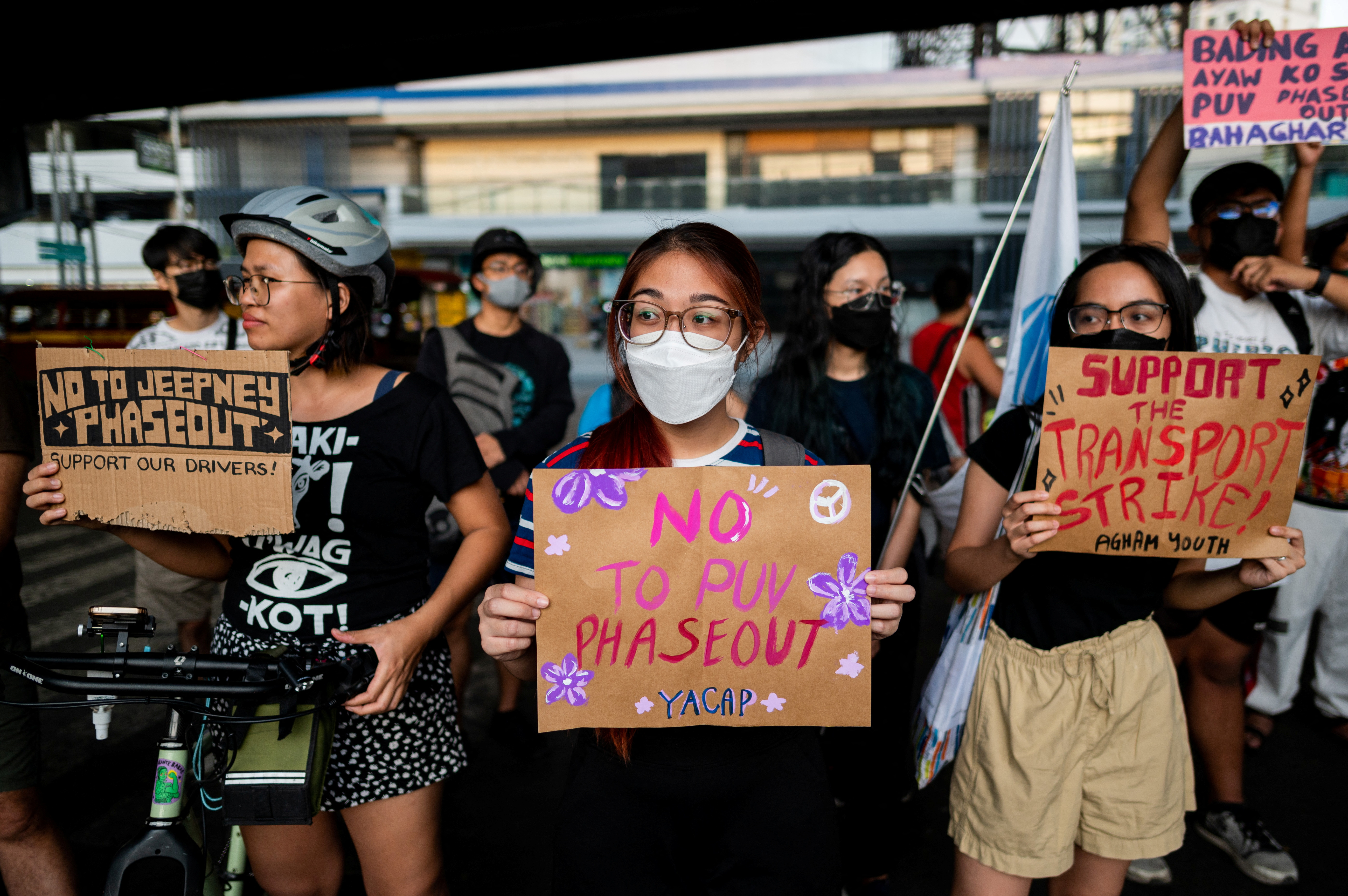 Protesters hold placards in support of the jeepney strike. The placards read 'No to Jeepney Phaseout" and 'Support the Transport Strike'