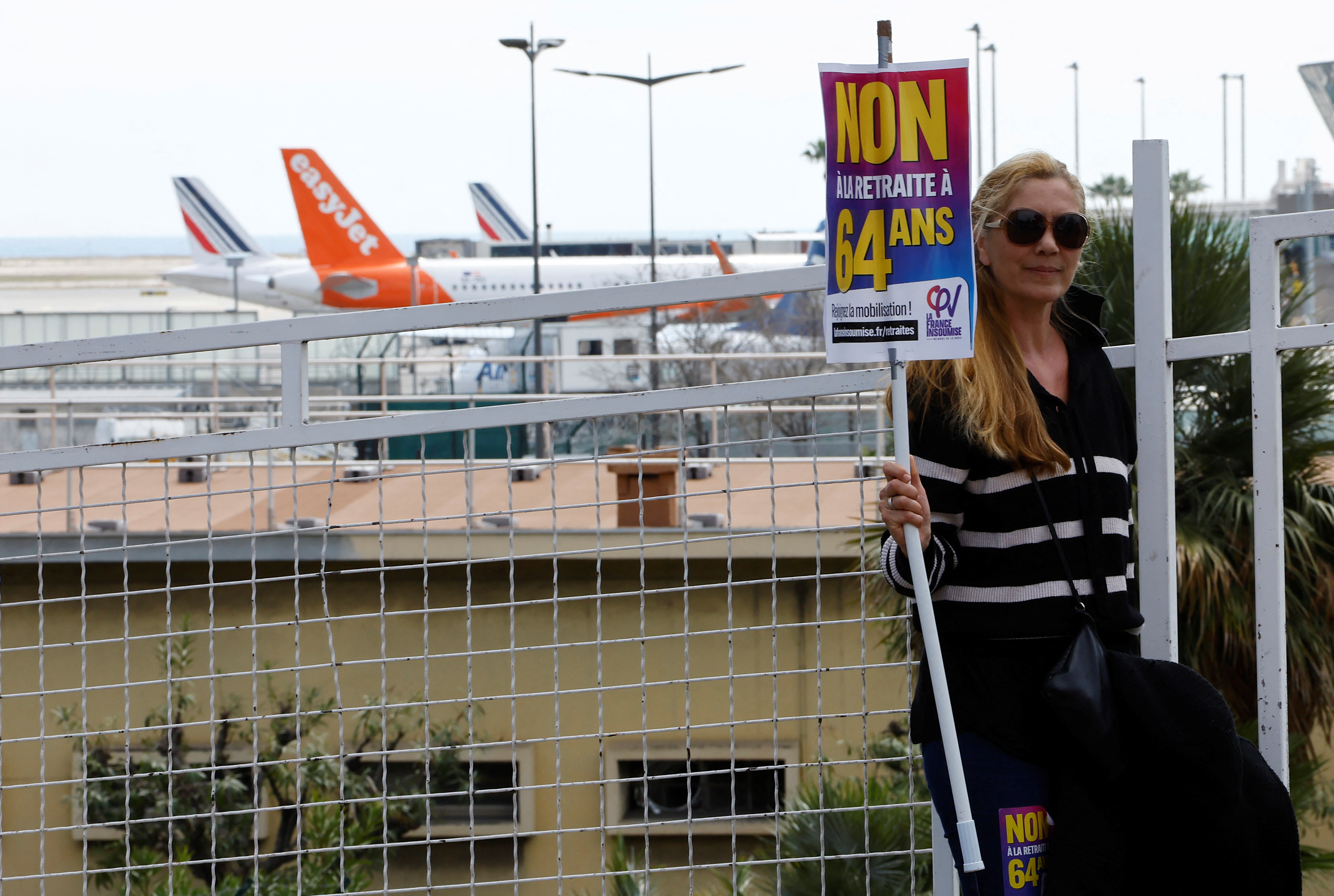 A protester, holding a placard which reads "No to 49.3", a special clause in the French Constitution, to push the pensions reform bill through the National Assembly without a vote by lawmakers, attends a demontration to block Nice international airport