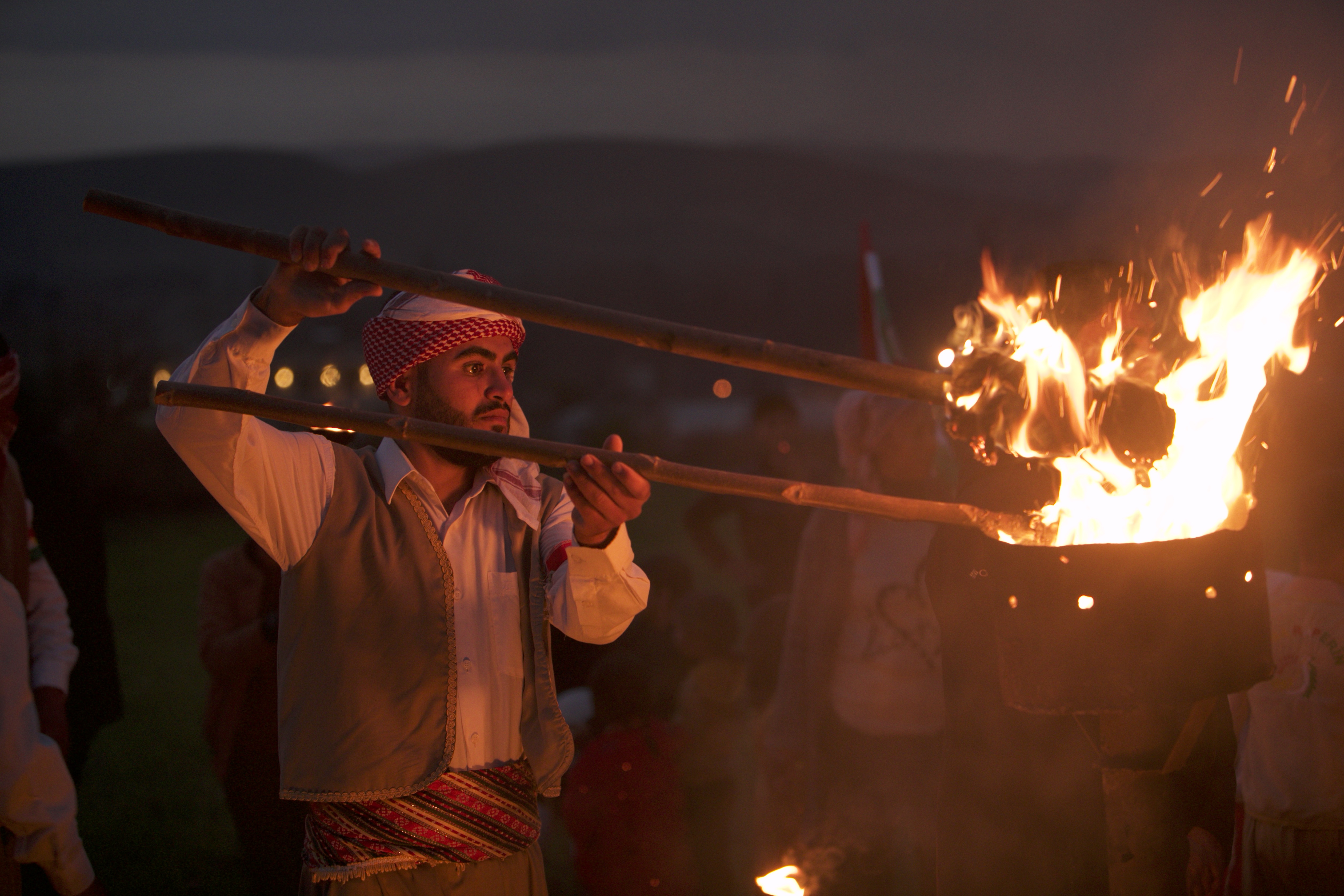 A man lights a fire with a torch in his hand