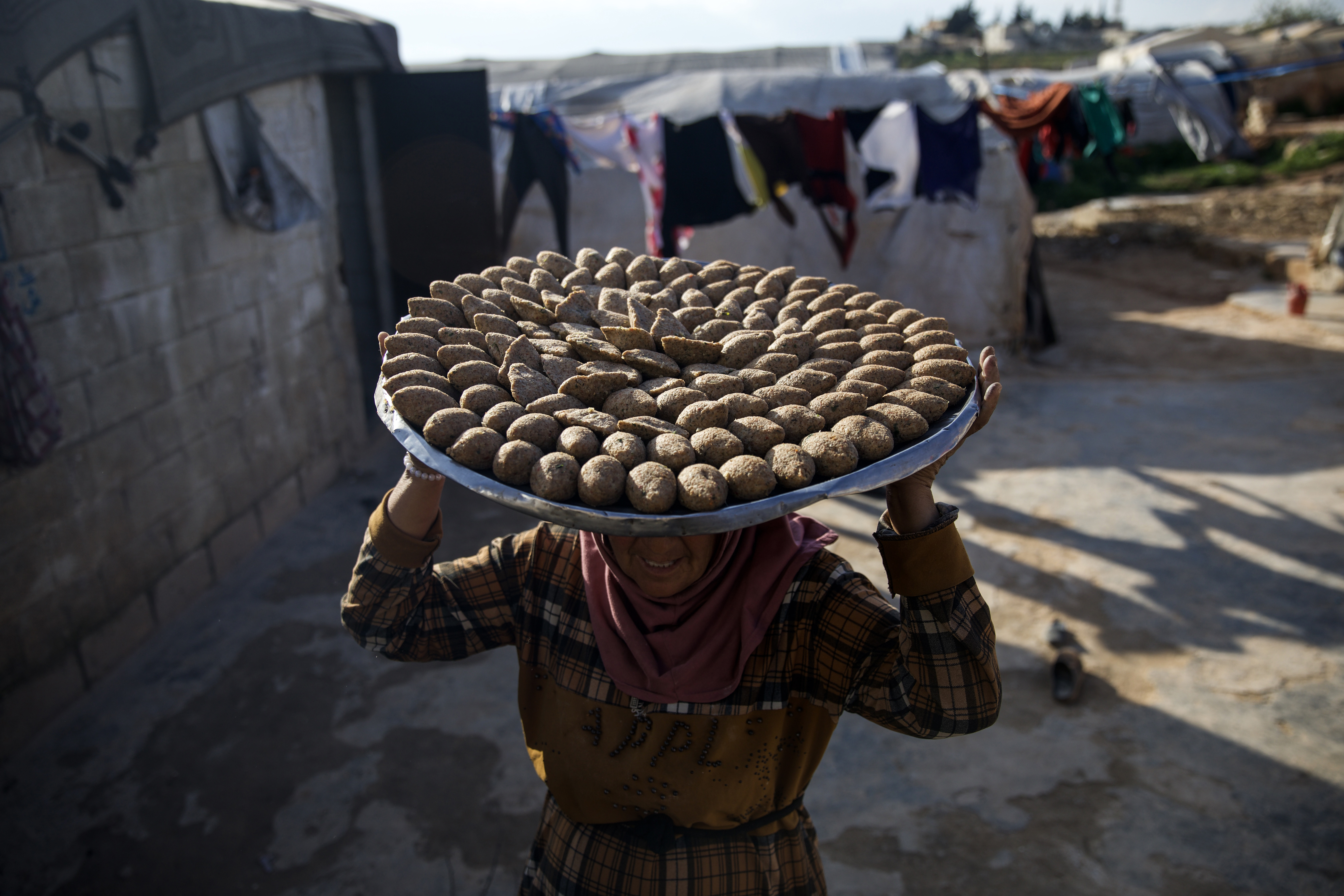 Fateem carries on her head a big tray with the kibbes on it to take outside to fry