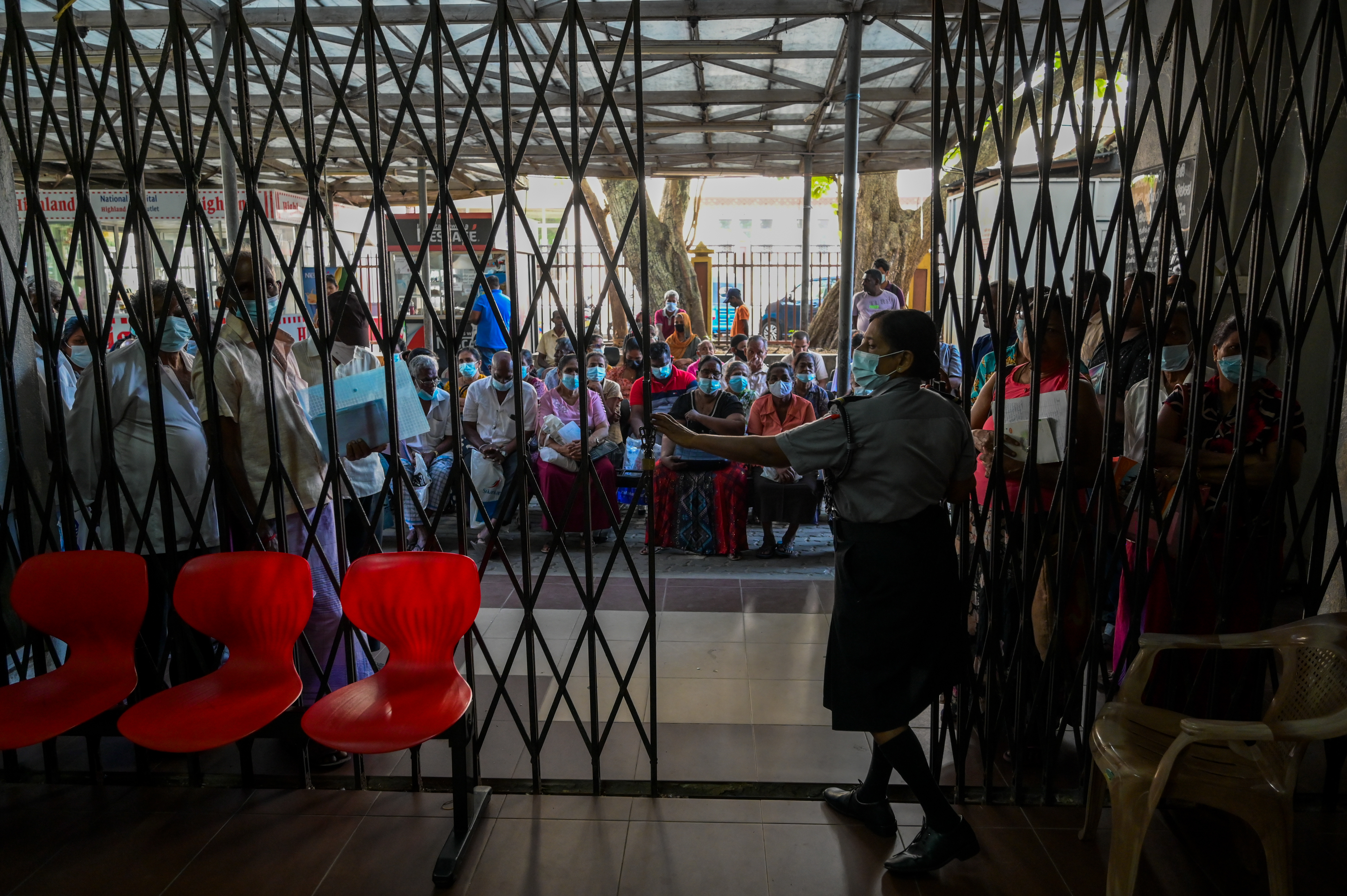 Sri Lankan patients wait for treatment behind the gates of an empty government hospital in Colombo