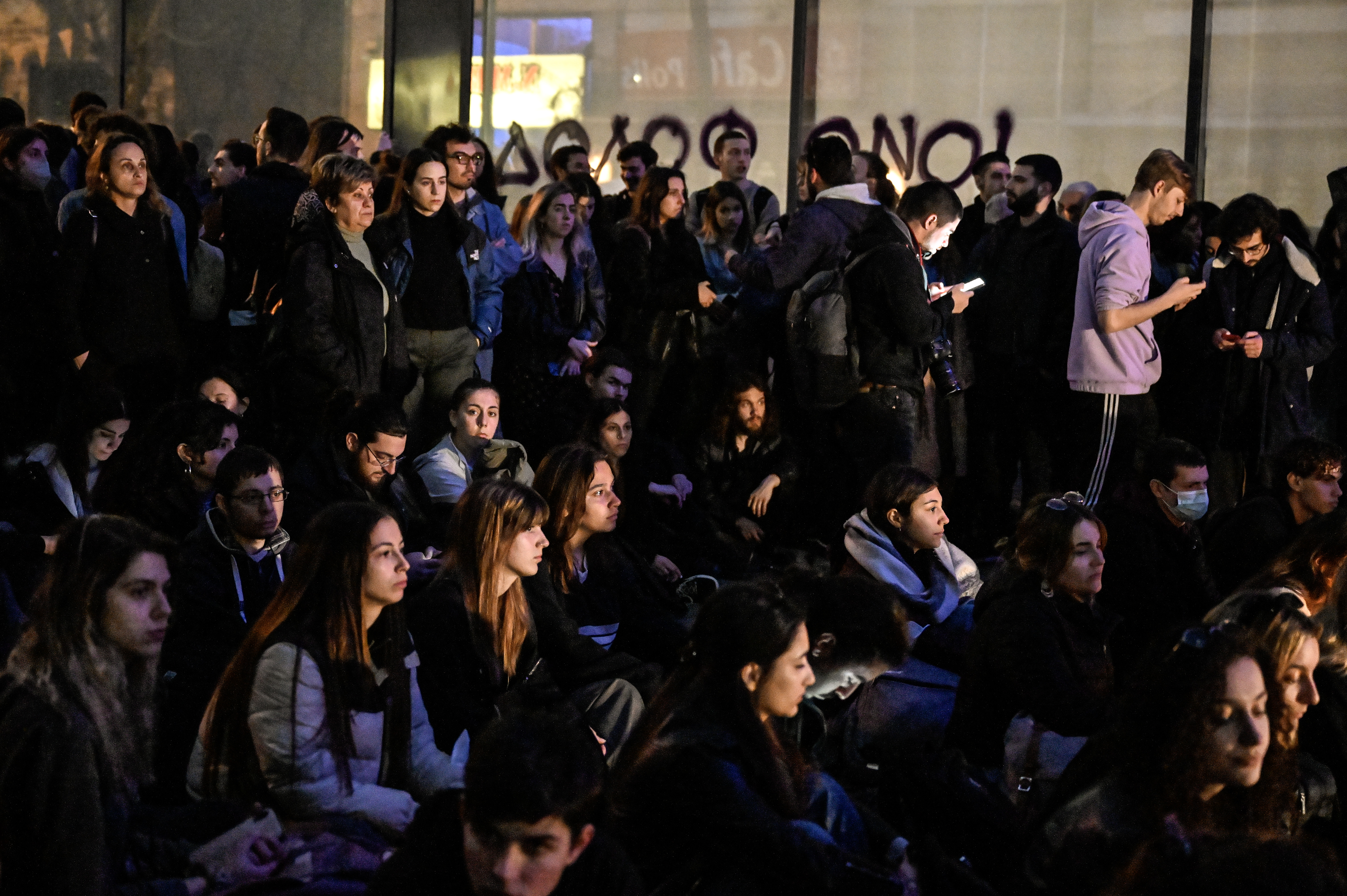 Students sit as they hold candles during a sit-in protest and tribute to the victims of a deadly train accident