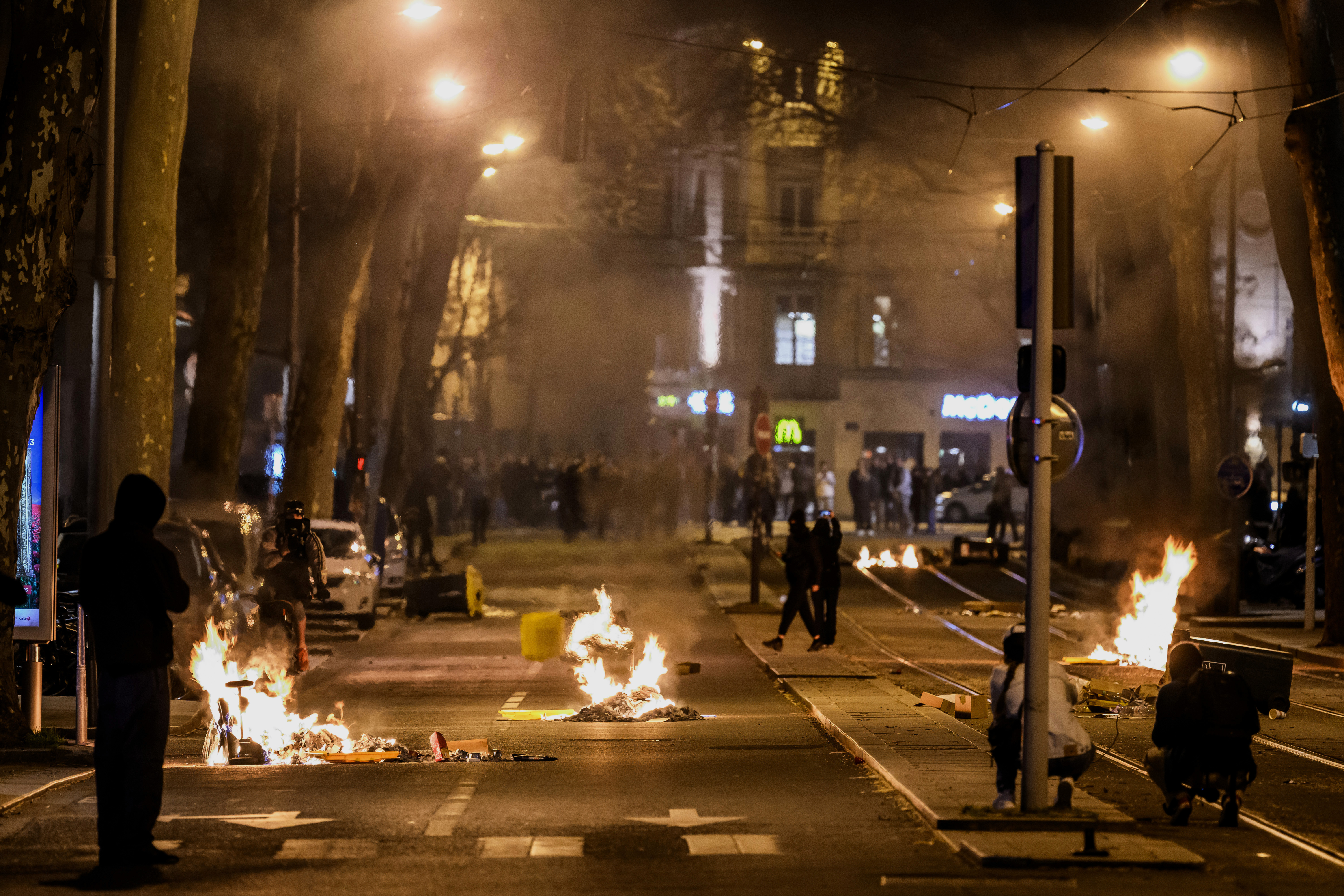 People walk past burning rubbish during a demonstration in Lyon, eastern France. 