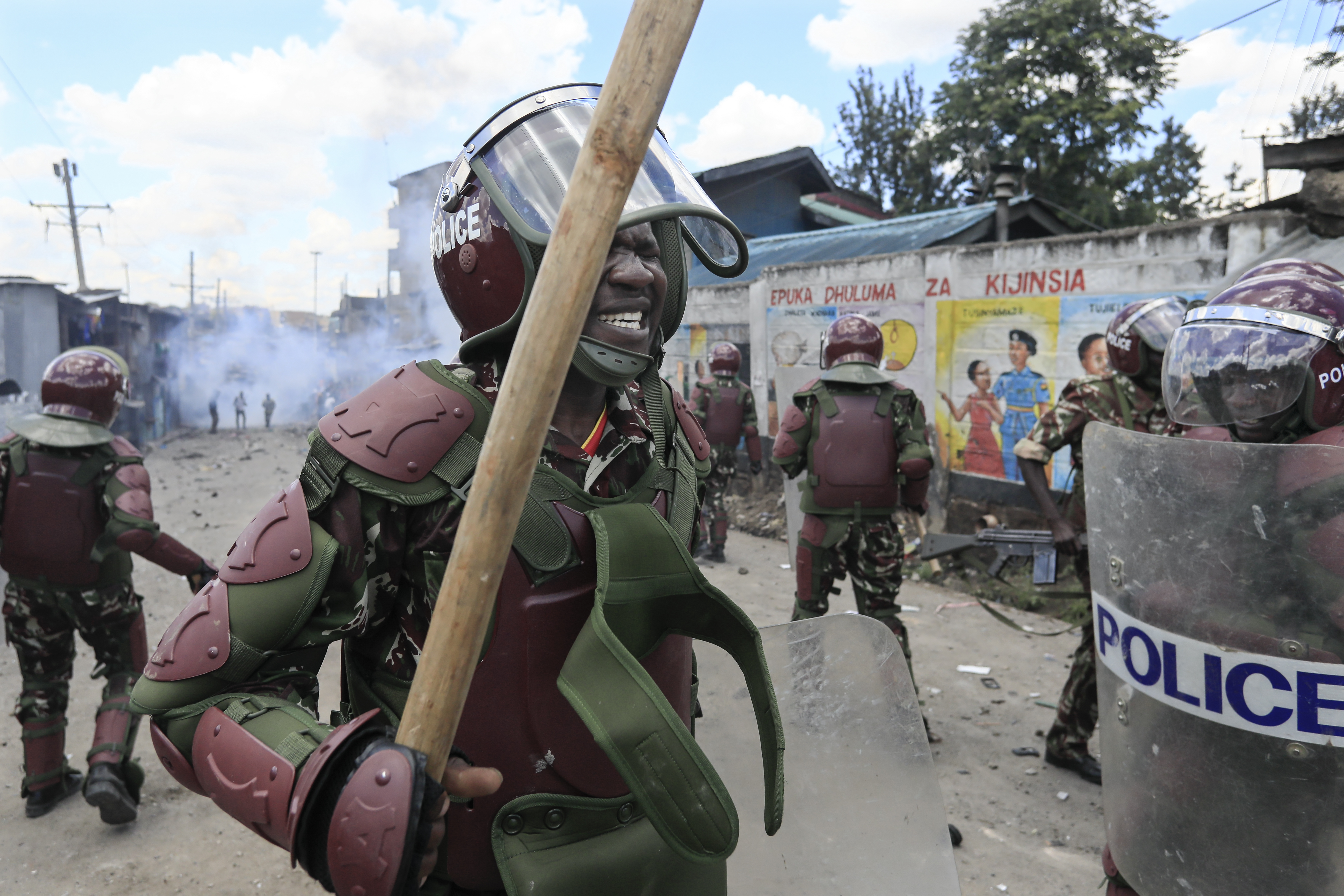 Anti-riot police officers react to the effects of tear gas after one of their canisters fired at protesters was lobbed back at them during confrontations at a mass rally called by opposition leader Raila Odinga, in Mathare, Nairobi, on March 27, 2023 [Tony Karumba / AFP]