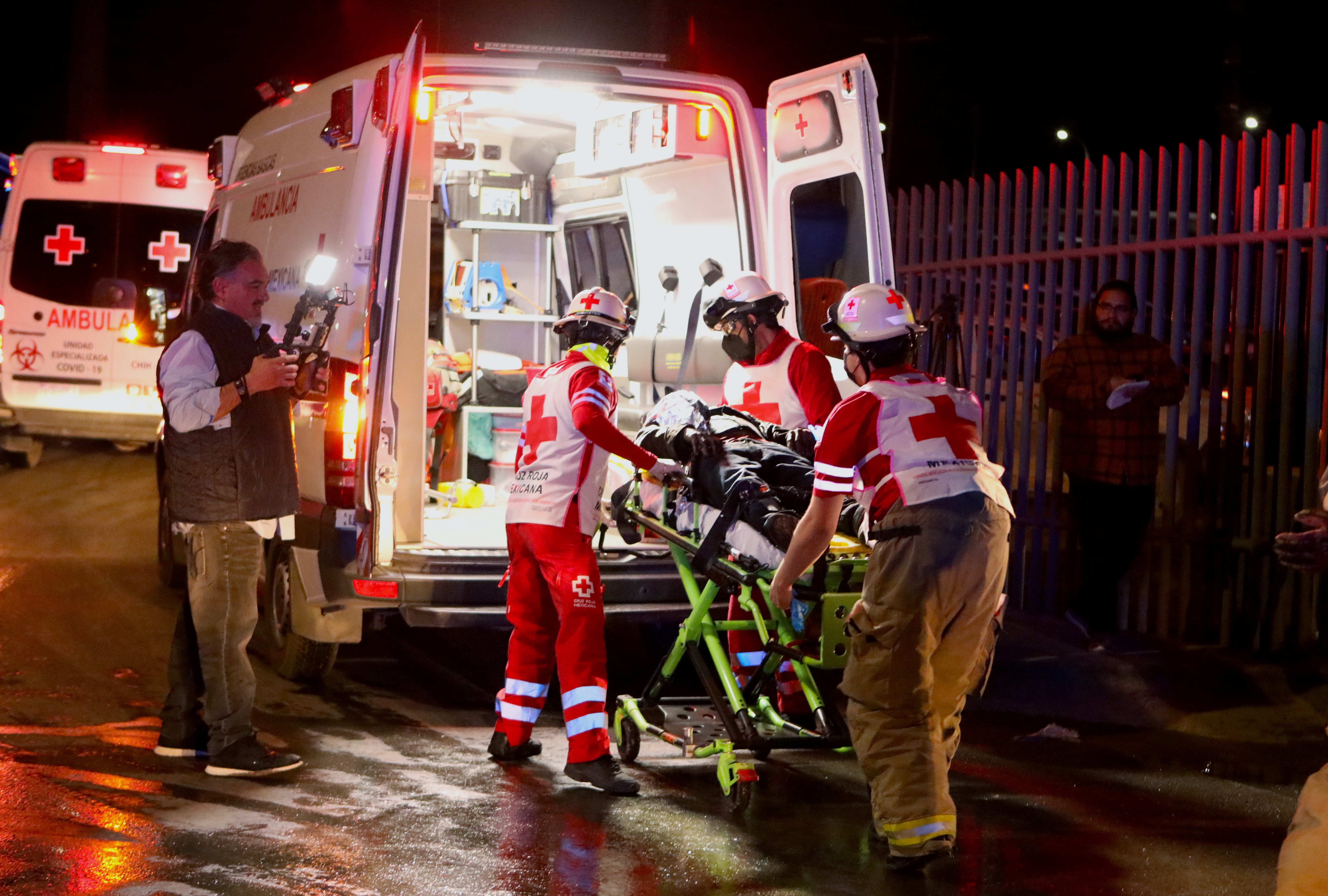 Paramedics carry an injured migrant following a fire that killed dozens of migrants, in the immigration station in Ciudad Juarez, Mexico