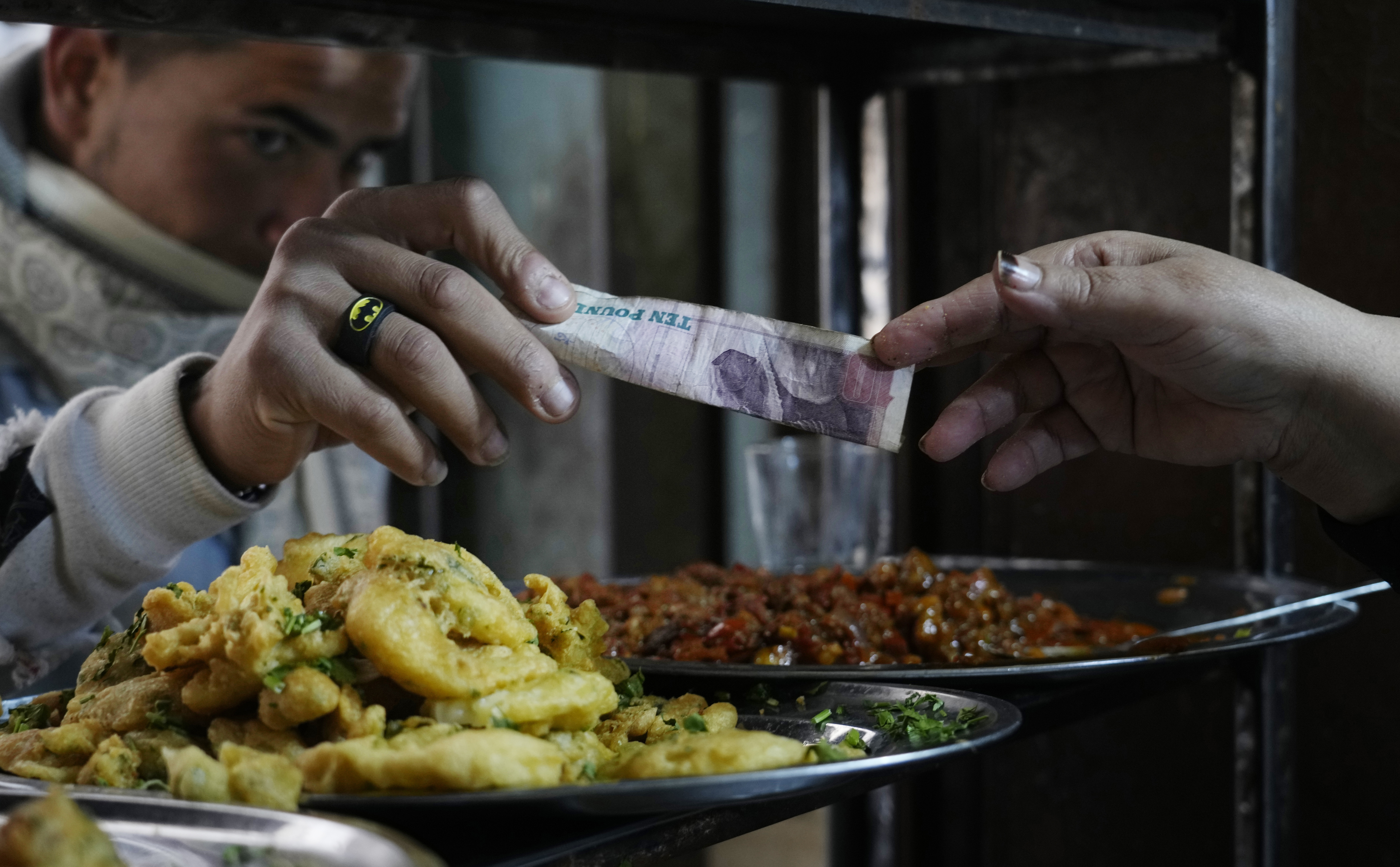 FILE - A man buys food at a restaurant in Cairo, Egypt, March 22, 2022. For decades, millions of Egyptians have depended on the government to keep basic goods affordable. But a series of shocks to the global economy and Russia's invasion of Ukraine have endangered the social contract in the Middle East's most populous country, which is also the world's biggest importer of wheat. It is now grappling with double-digit inflation and a steep devaluation of its currency. (AP Photo/Amr Nabil, File)