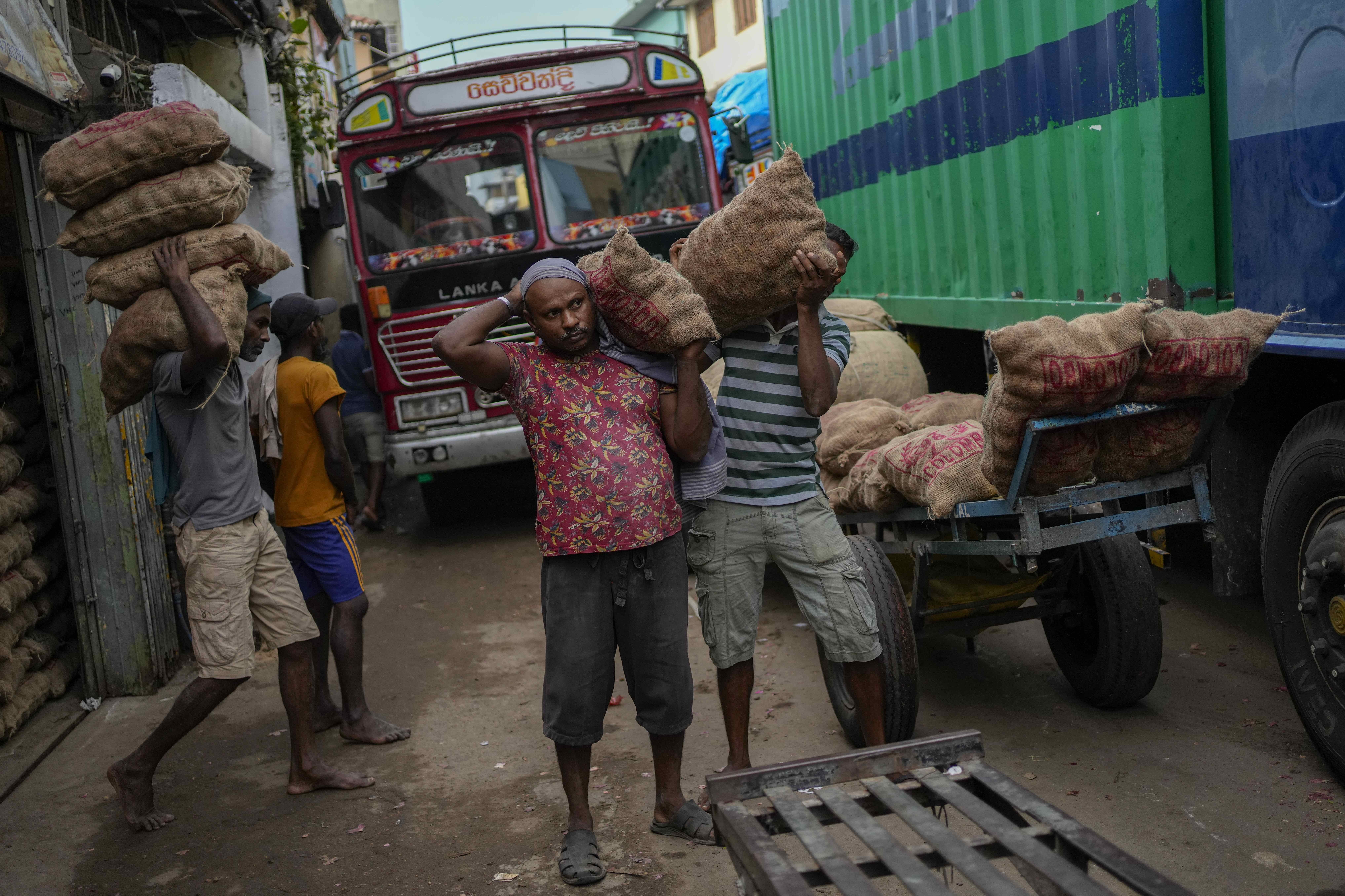 Laborers load sacks of imported potatoes to hand carts at a market place in Colombo, Sri Lanka, Tuesday, March 21, 2023.