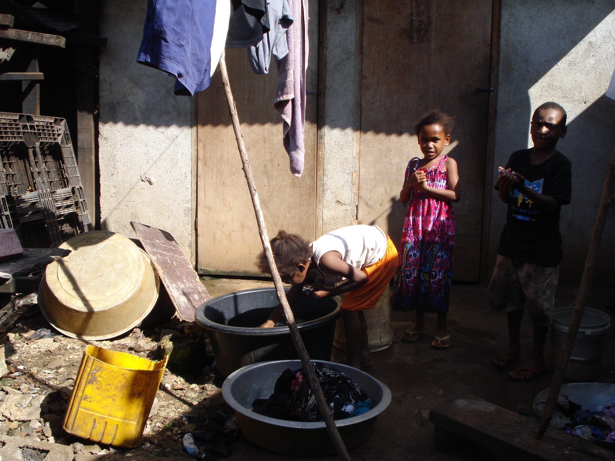 Three children in an informal settlement on the outskirts of Port Vila, where there is precarious housing.