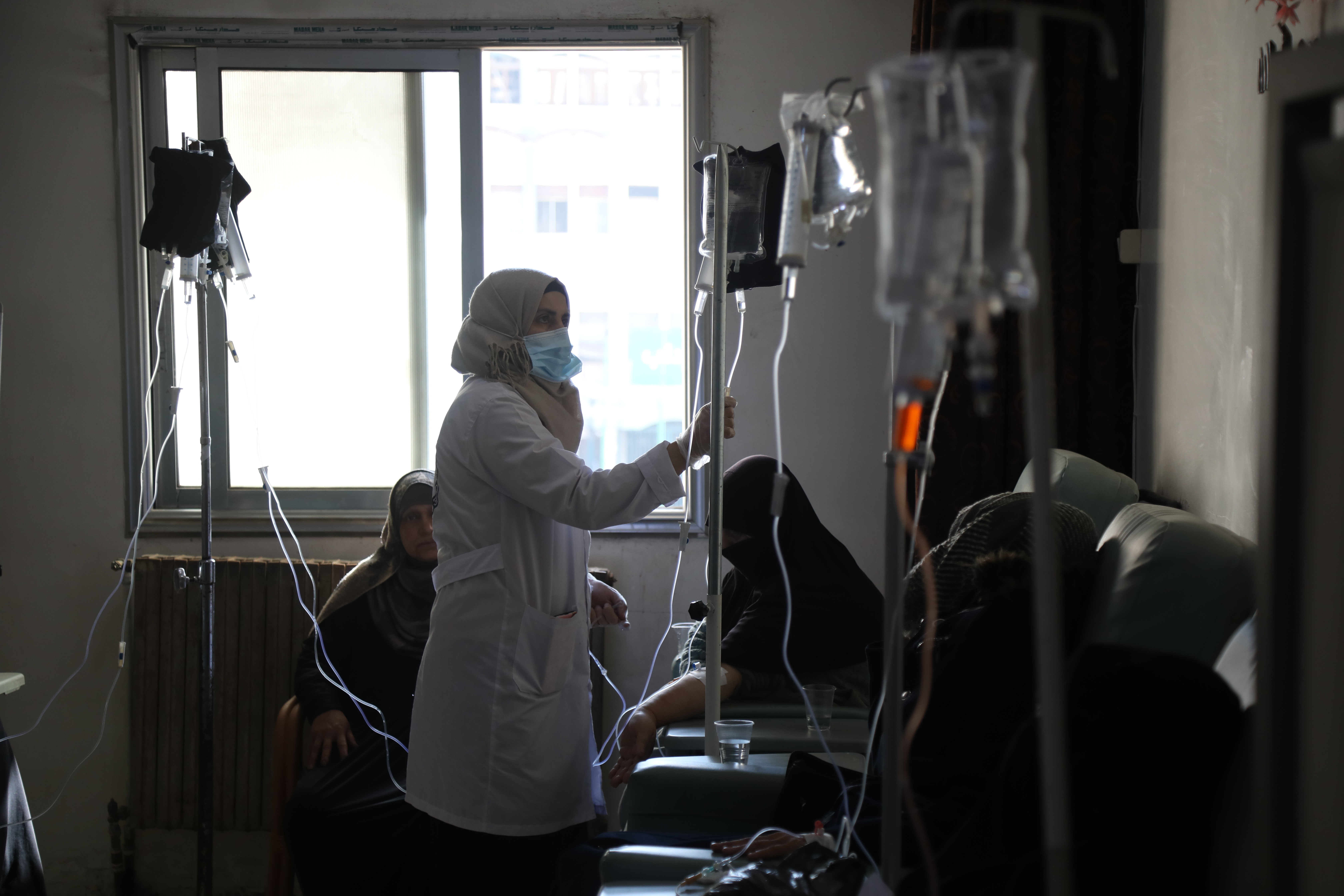 A doctor adjusts the IV drip administering chemotherapy to a patient