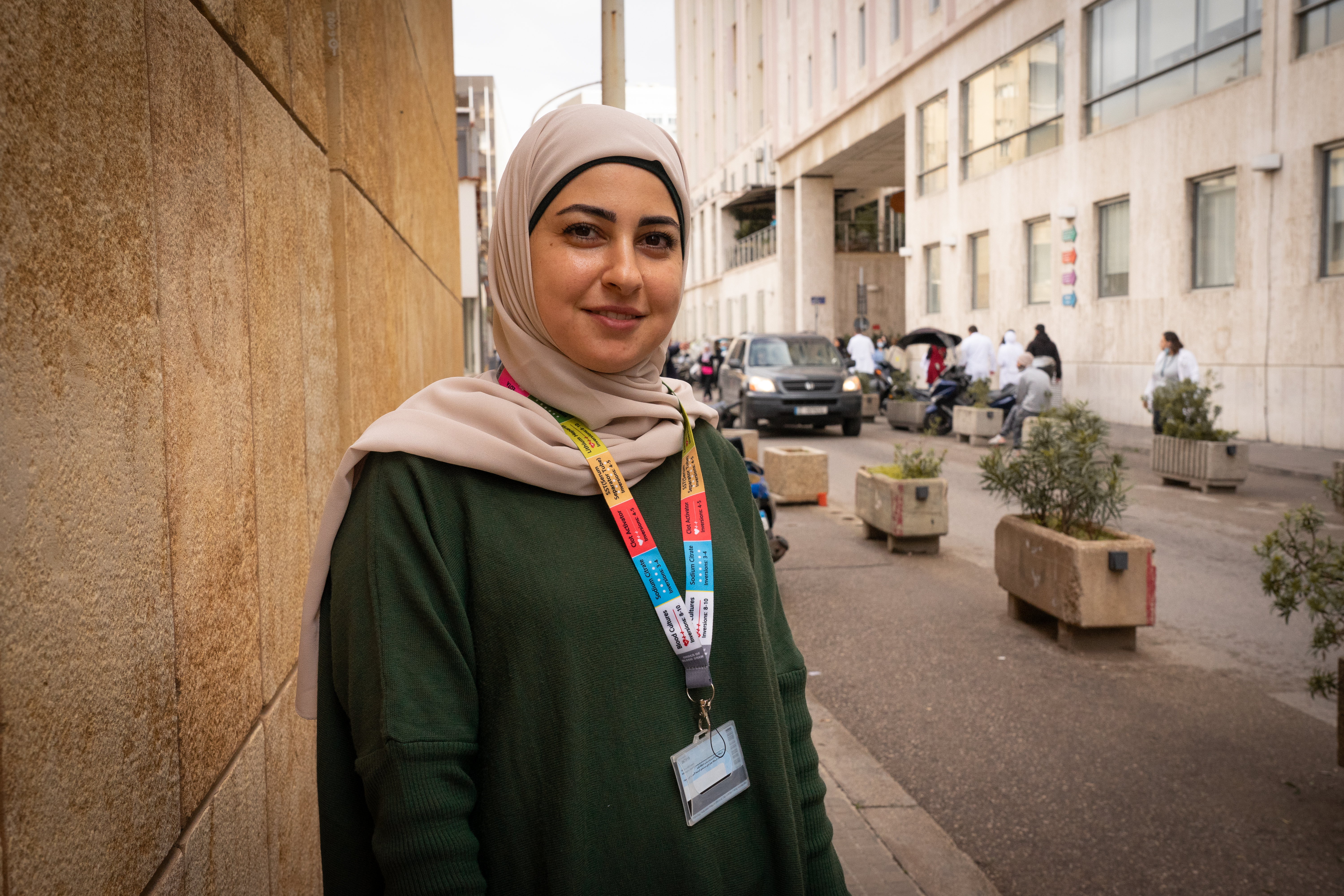 A woman standing on the side of a street looks into the camera