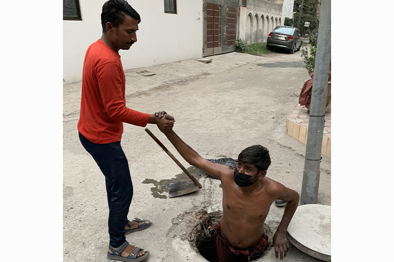 A photo of someone pulling a man out of a hole in the ground.