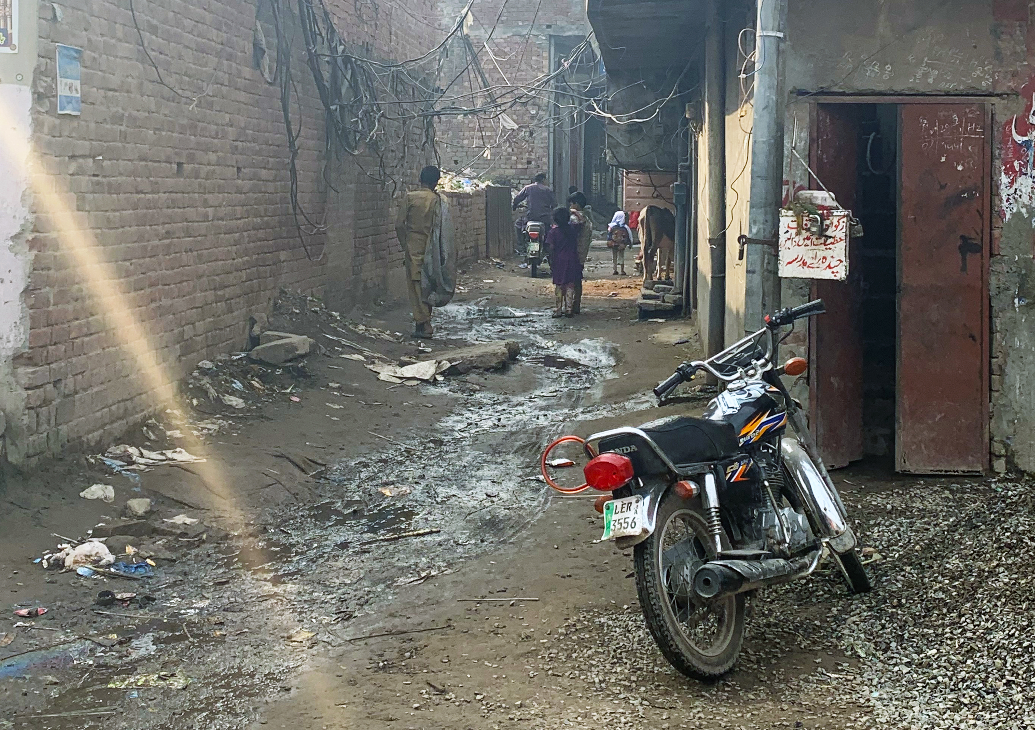 A photo of an alleyway with an electric bike in the forefront and people walking in the alley.