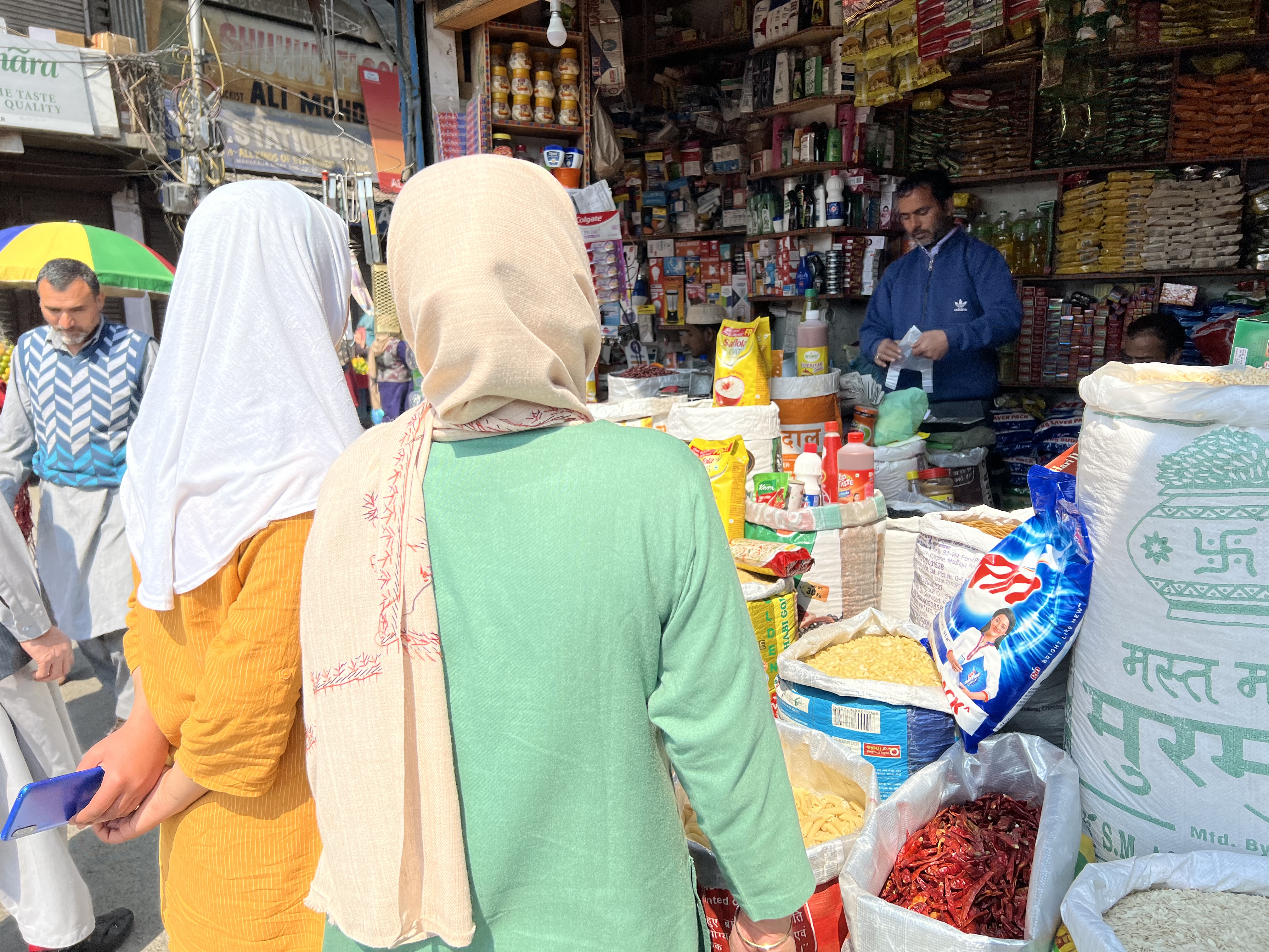 A photo of people buying groceries from a seller at an outdoor market.