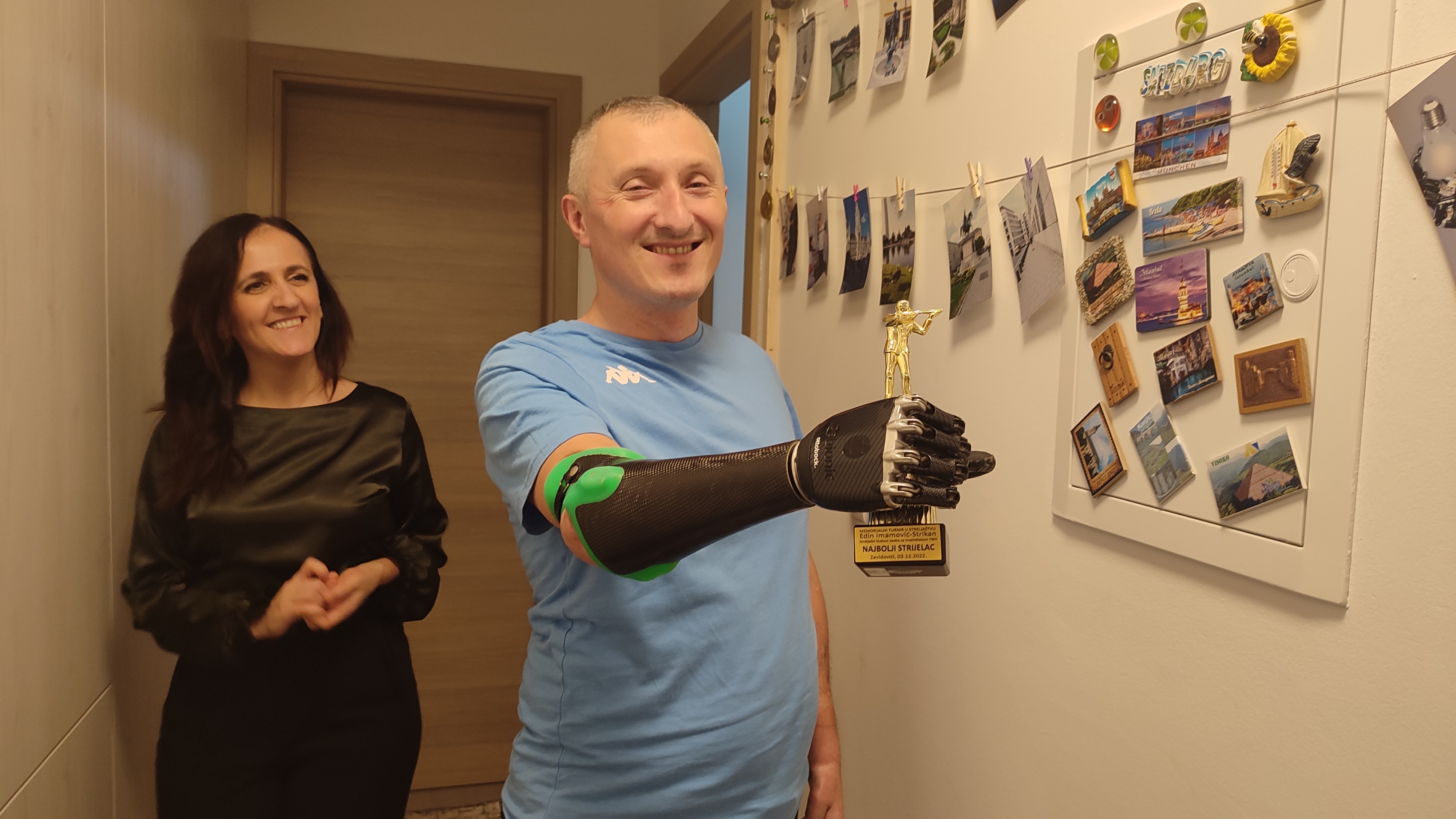 A man holds a trophy with his wife next to him