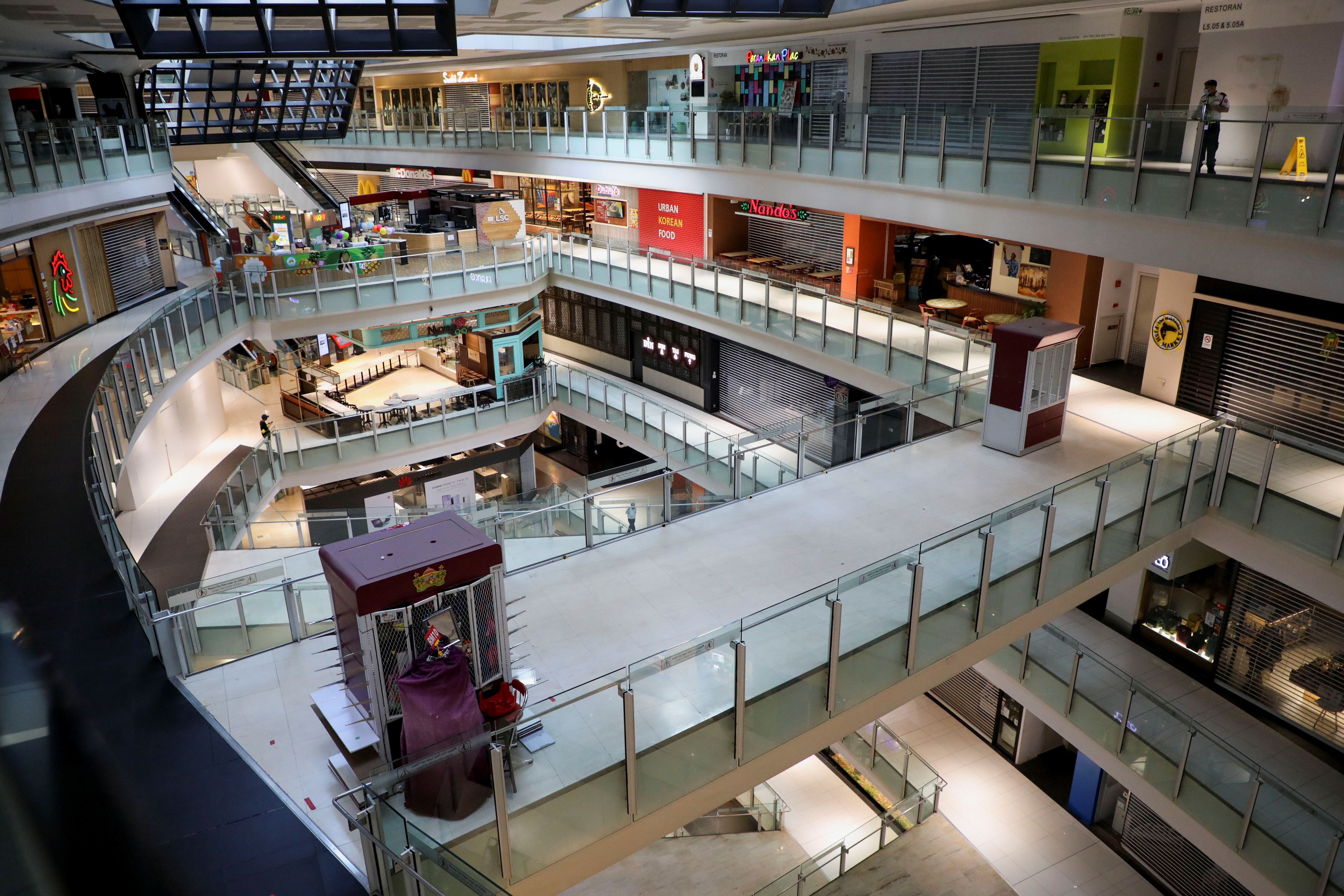 Inside of a shopping mall seen from a top floor, showing several floors below with no customers