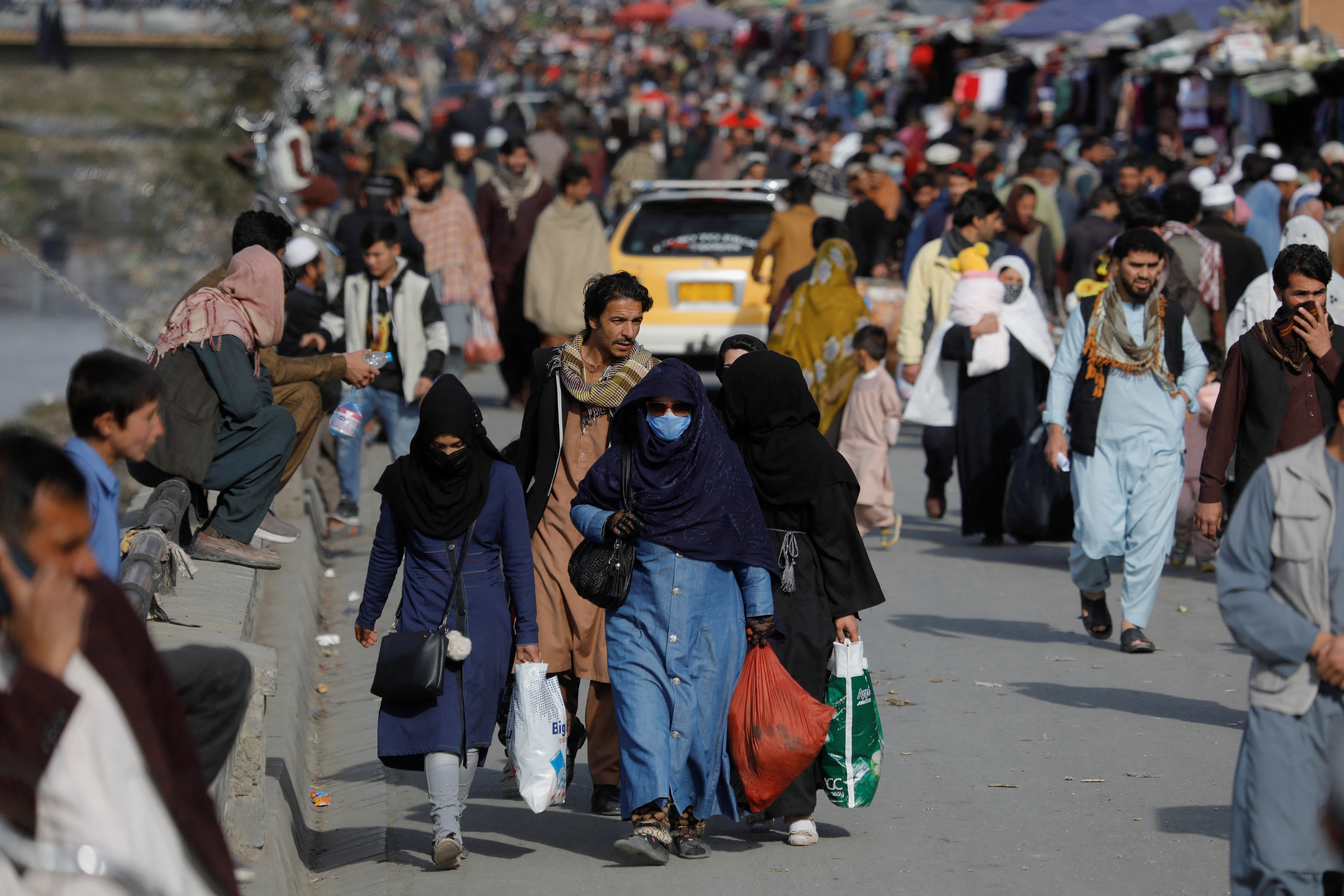 A few women walk on a Kabul street. Their heads are covered.