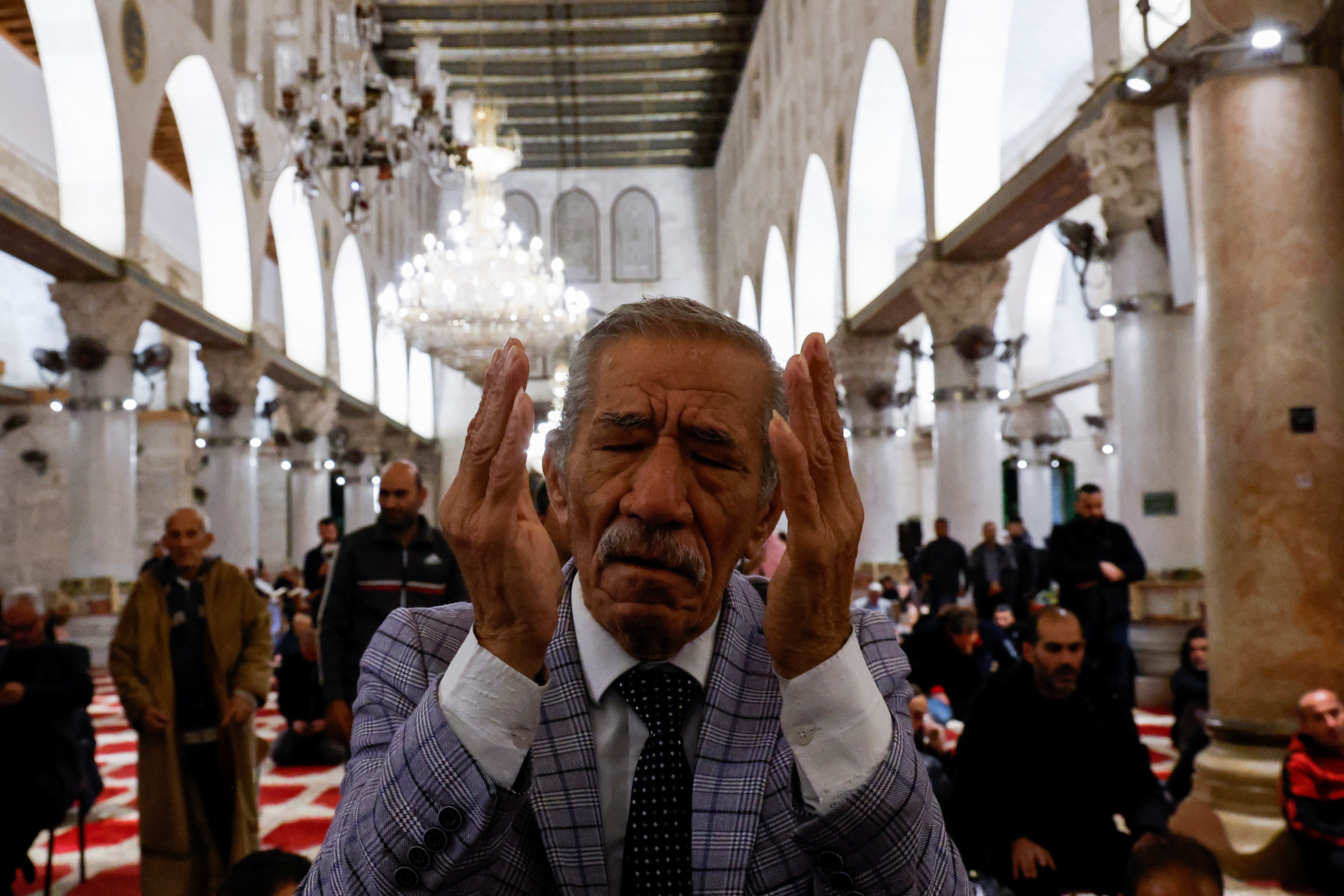 A Palestinian man prays as Israeli security forces take position at the Al-Aqsa compound,