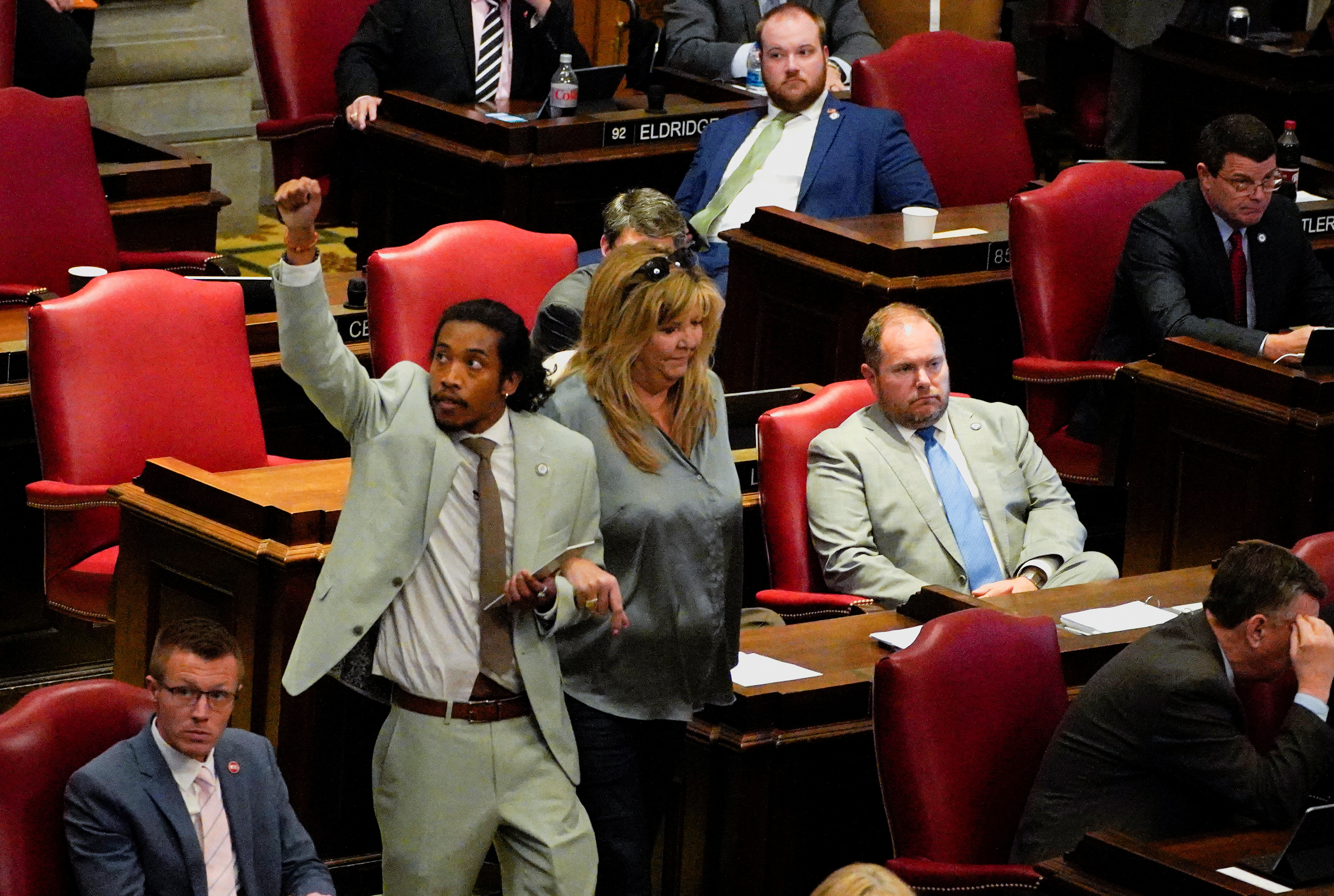 Justin Jones lifts a fist as he makes his way down the aisle of the state House of Representatives