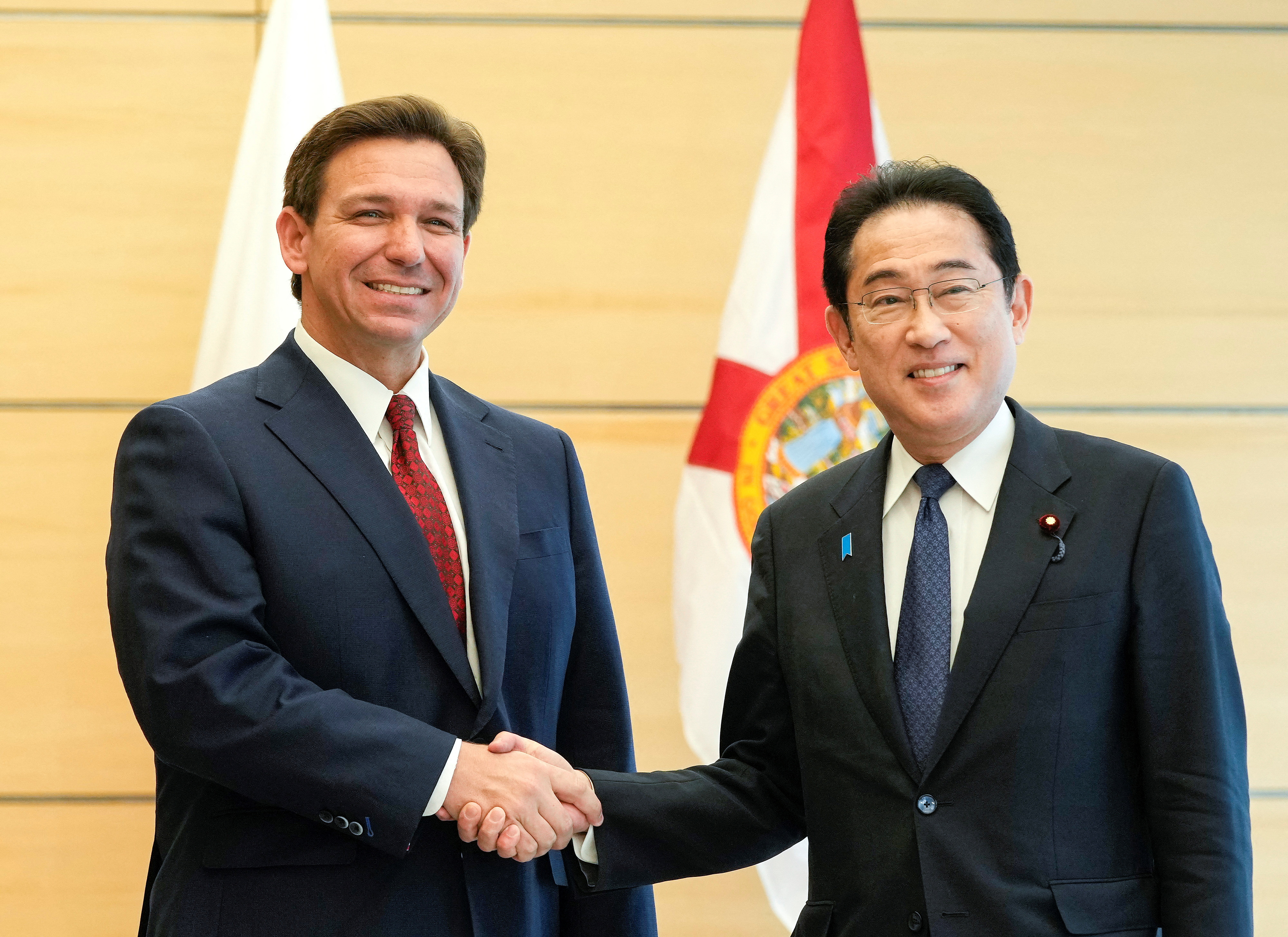 Florida Governor Ron DeSantis meets Japanese Prime Minister Fumio Kishida. They are shaking hands and smiling.