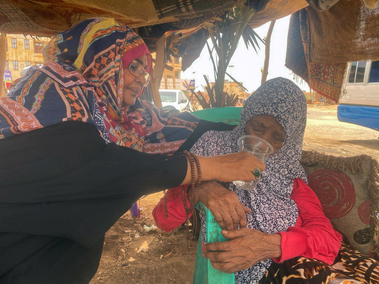 A woman is helped to drink water as she flees clashes between the paramilitary Rapid Support Forces and the army in Khartoum, Sudan.