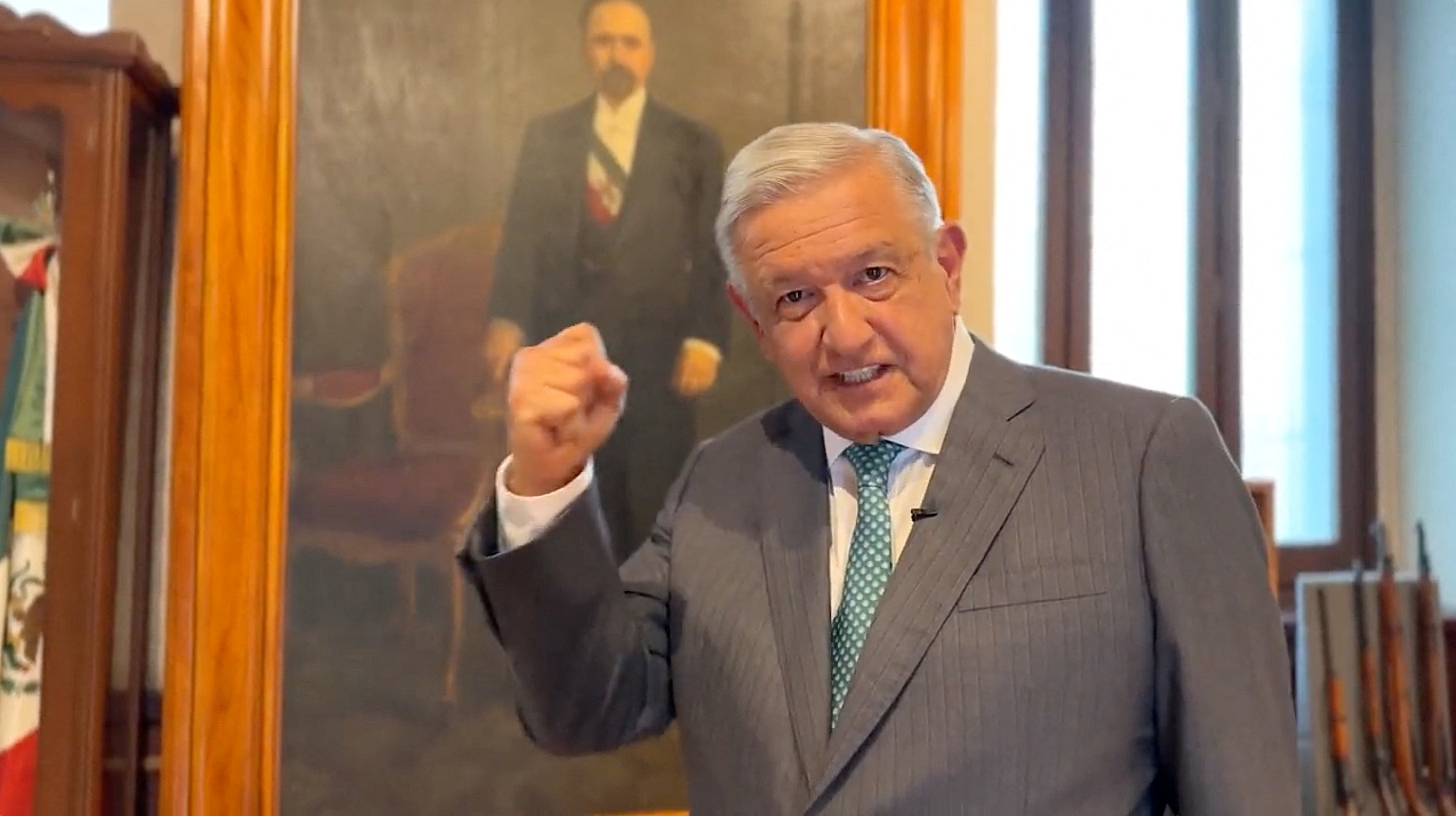 The Mexican President pumps his first in front of a painted portrait