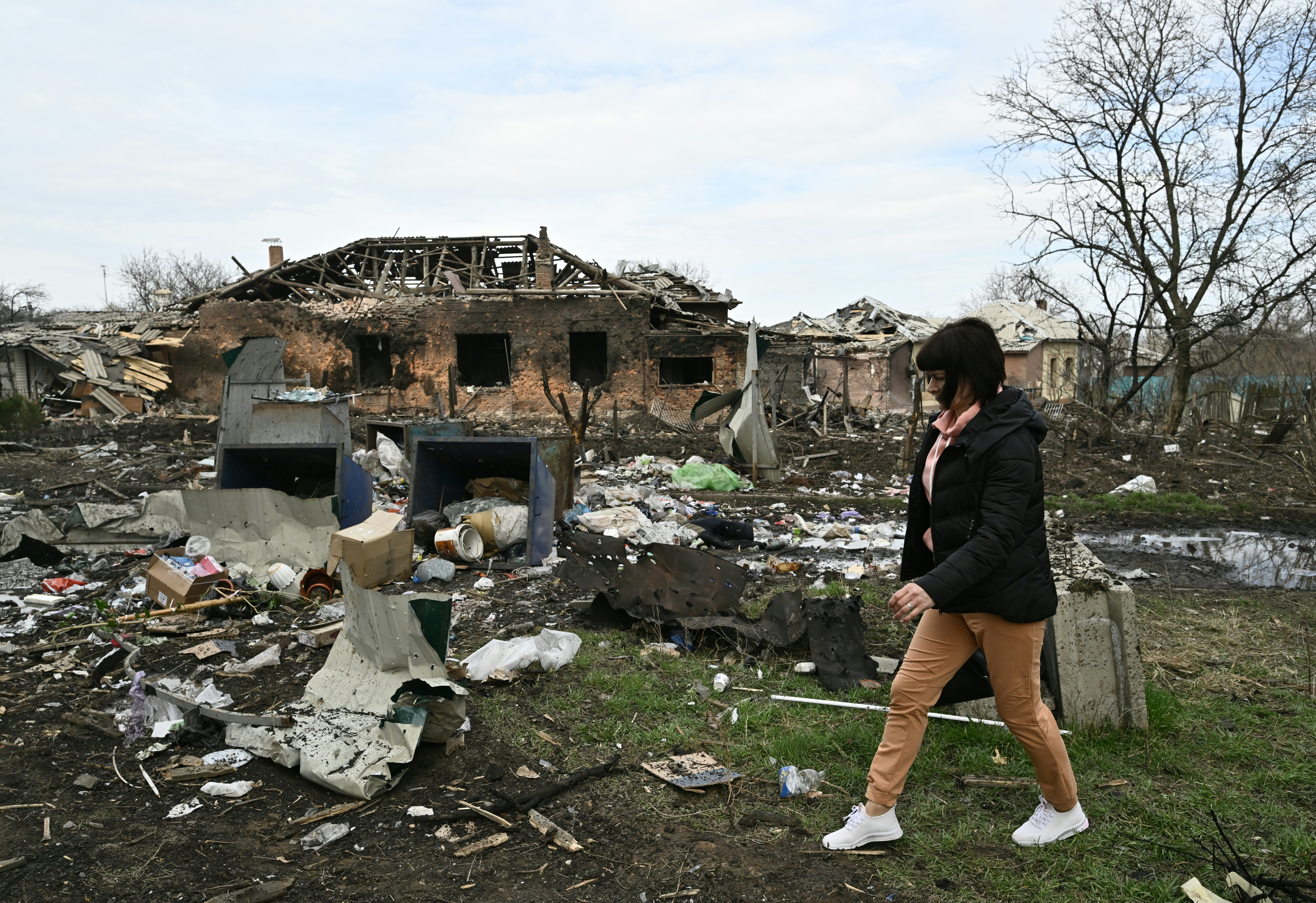 A local resident walks next to a damaged house.