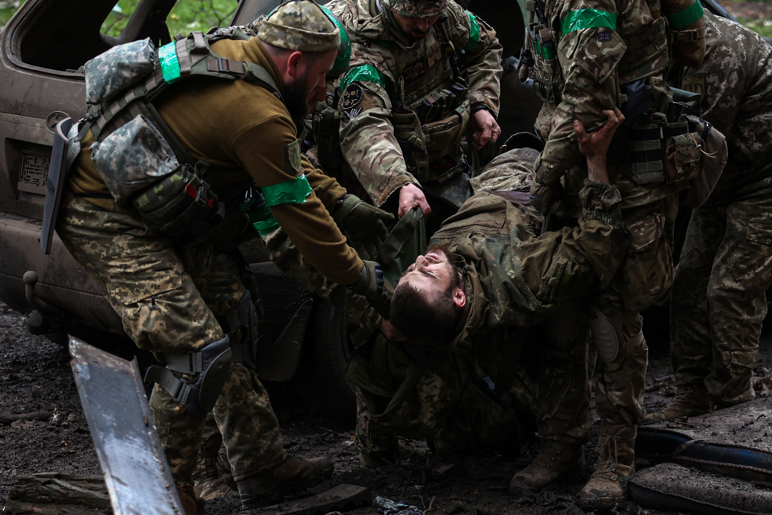 Ukrainian servicemen carry an injured comrade on a street in the frontline city of Bakhmut