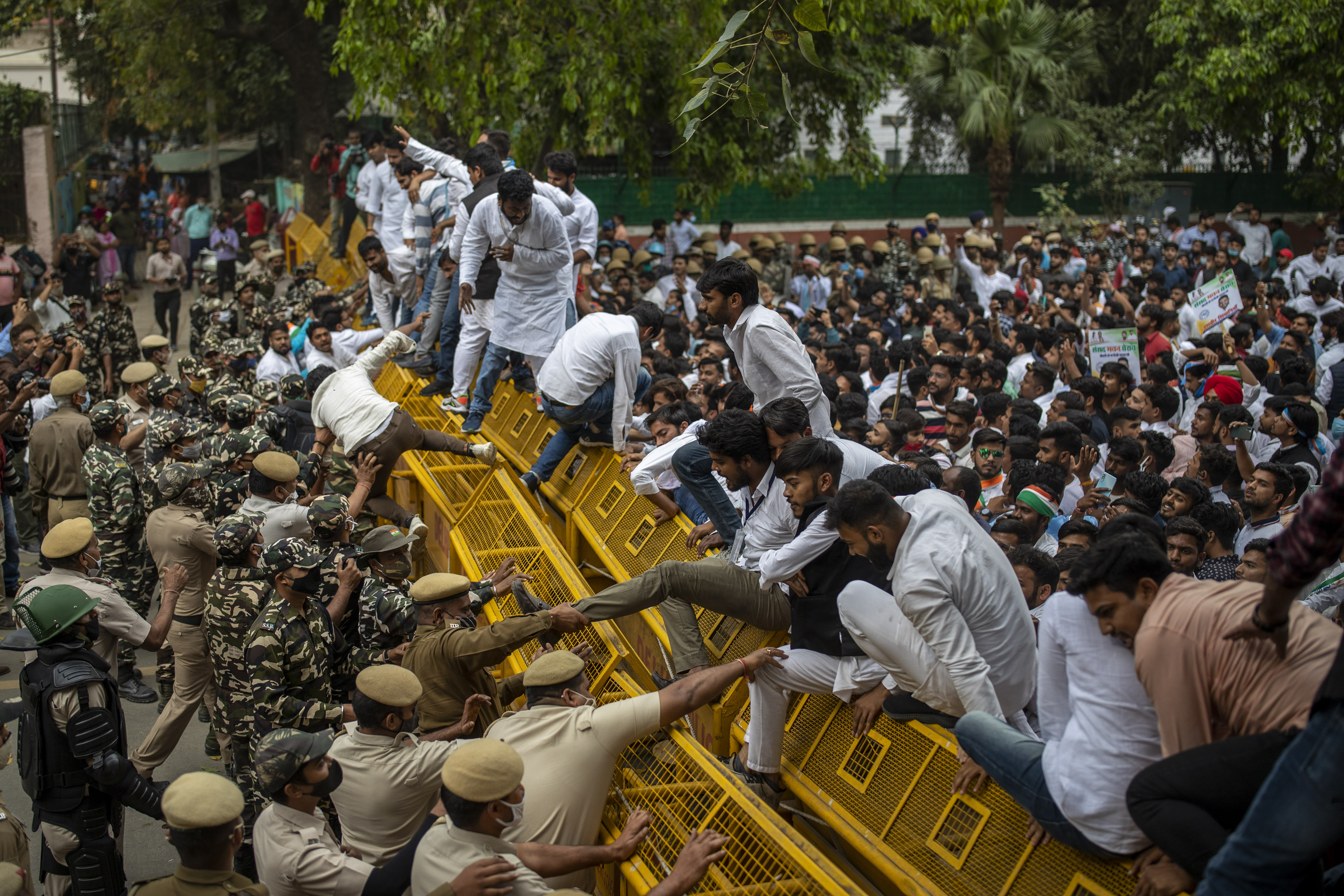 Indian police officers try to pull down members of National Students Union of India (NSUI), the student body of the Congress party, who climbed on police barricades during a protest against rising unemployment in the country in New Delhi, India, Friday, March 12, 2021. (AP Photo/Altaf Qadri)