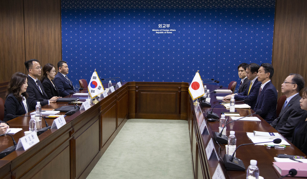 Japanese and South Korean officials sit across from each other during a meeting