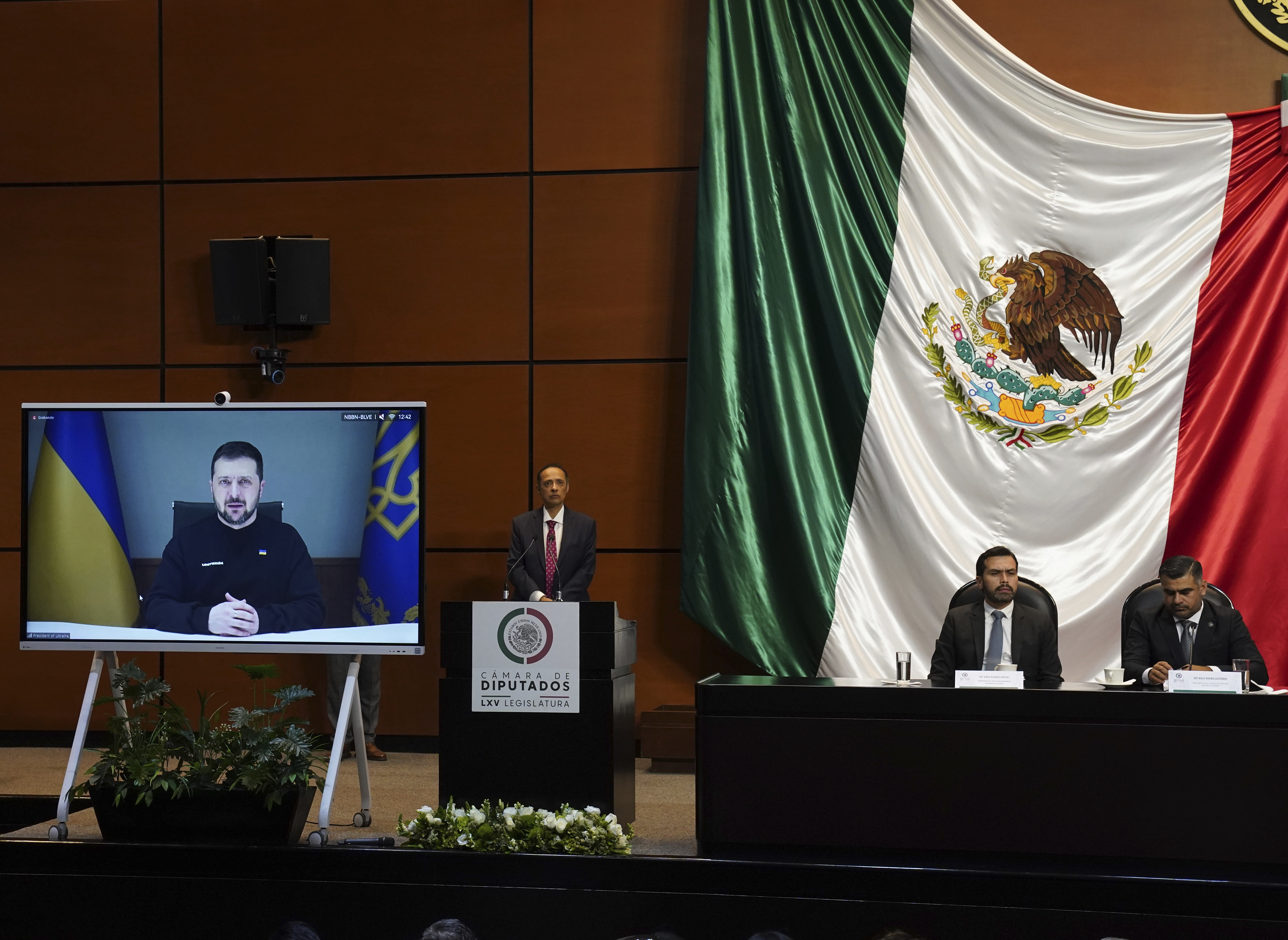 A screen positioned in front of Mexico's lower chamber of Congress, with a big Mexican flag draped against the wall