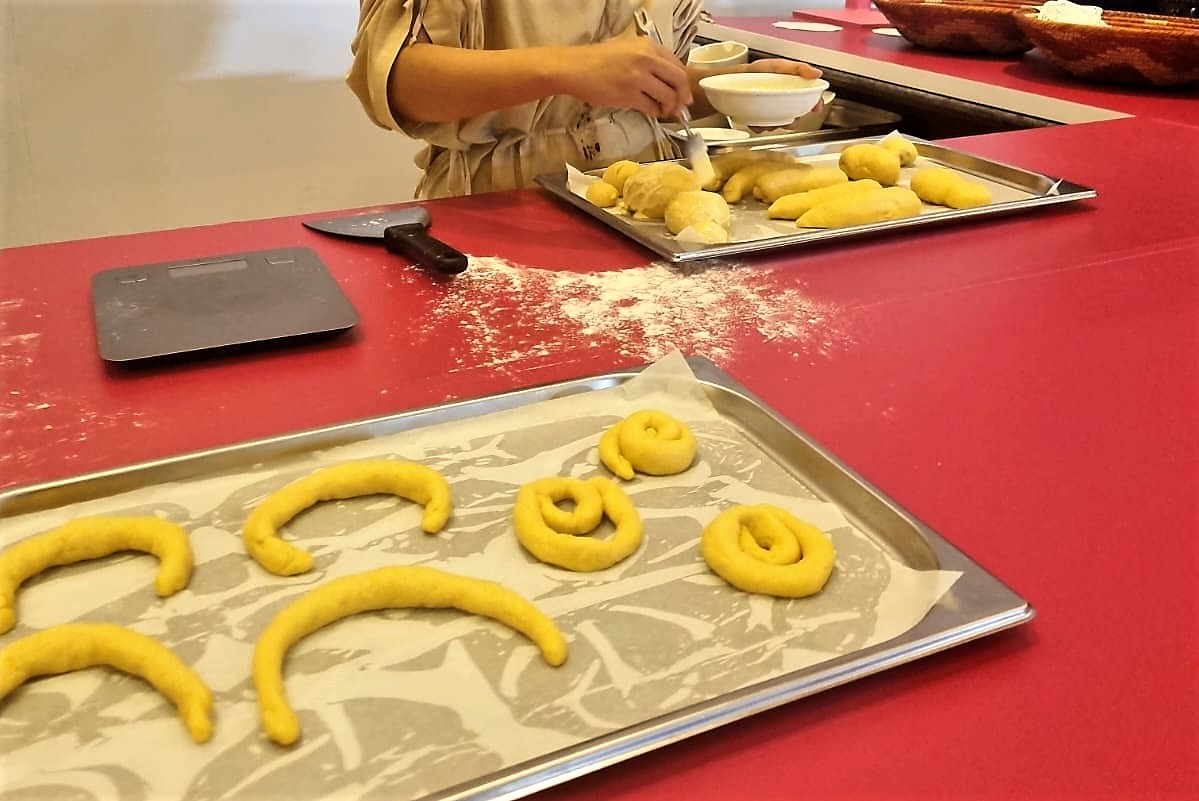 The artist's hands as she brushes eggwash over her shaped breads