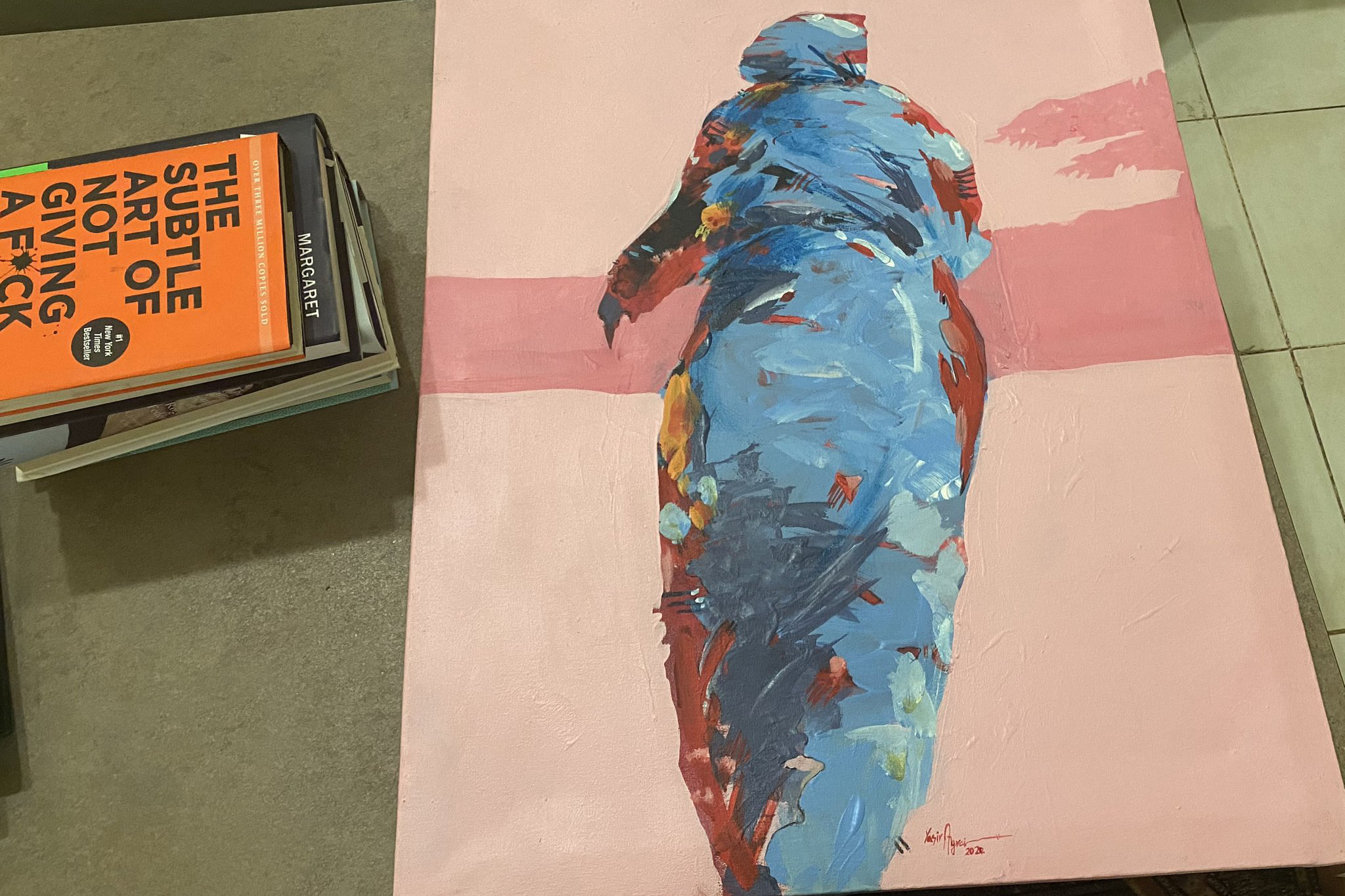 A painting on a table by a stack of books