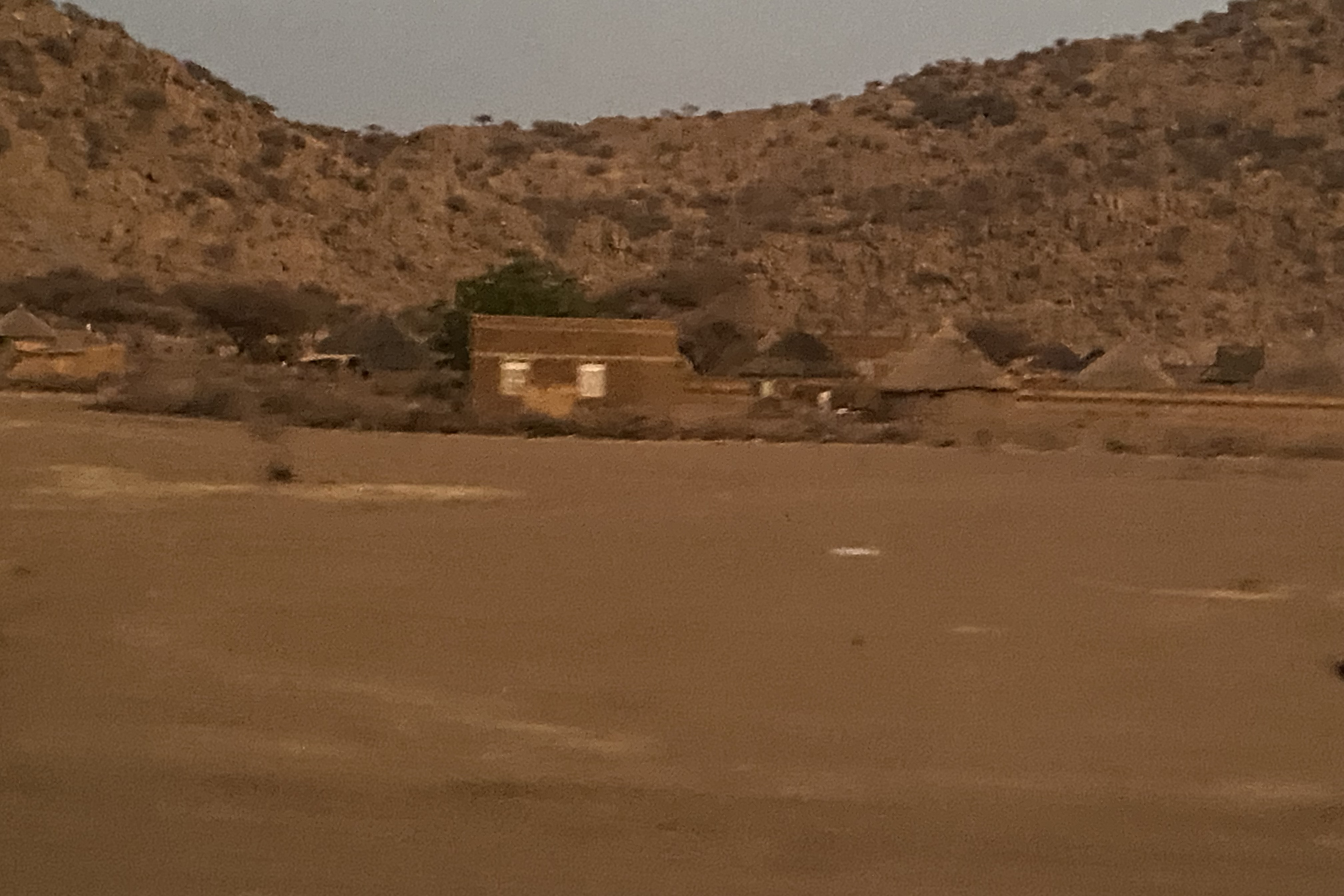 mud huts in the dusk with hills behind