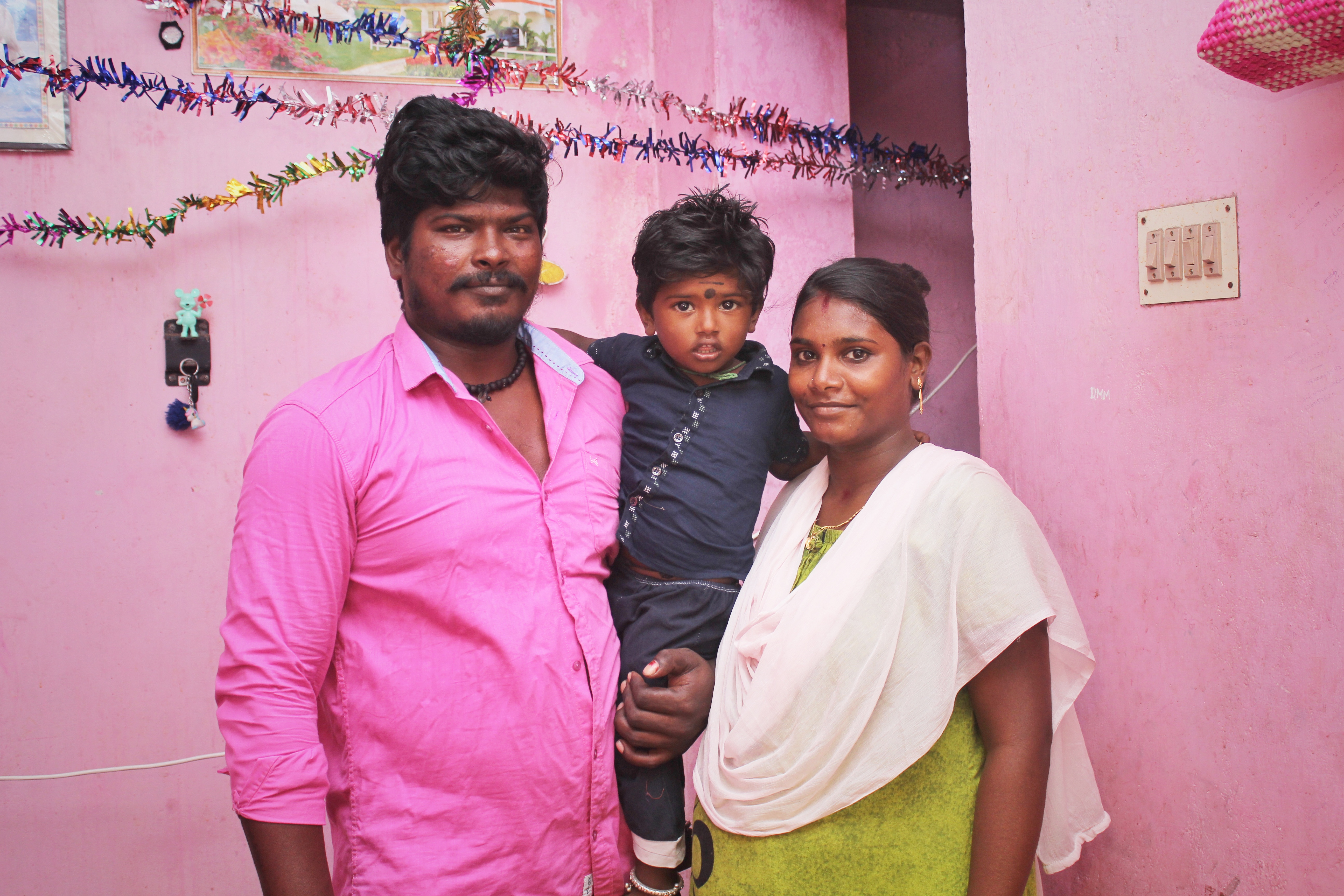 A photo of a family of three, the man on the left, the woman on the right and the child in between, being carried by his father.