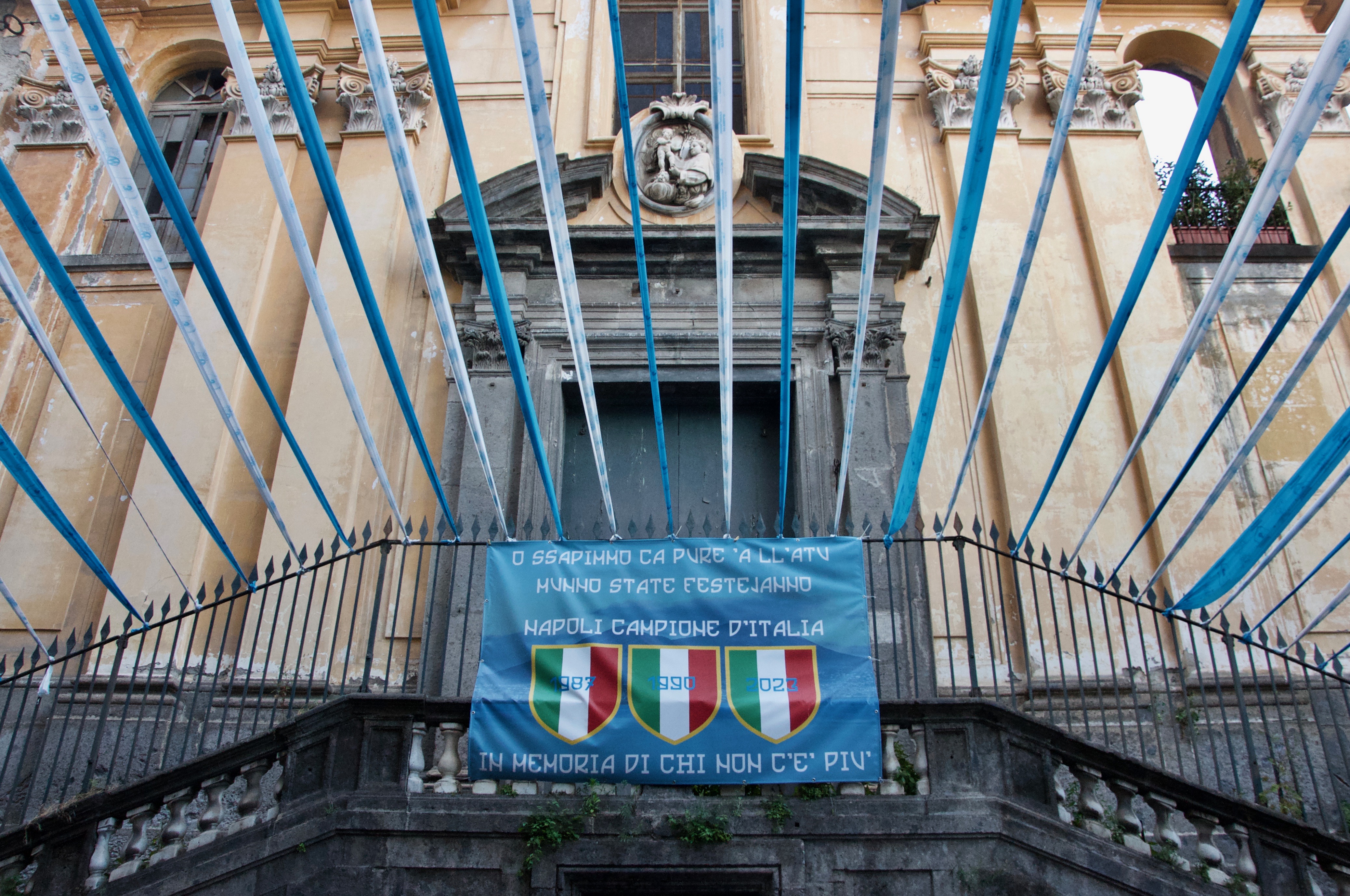 A banner outside a church in the Salvator Rosa neighborhood reads in the Neapolitan language: “And we know that even on the other side of the world, you all will be celebrating.”