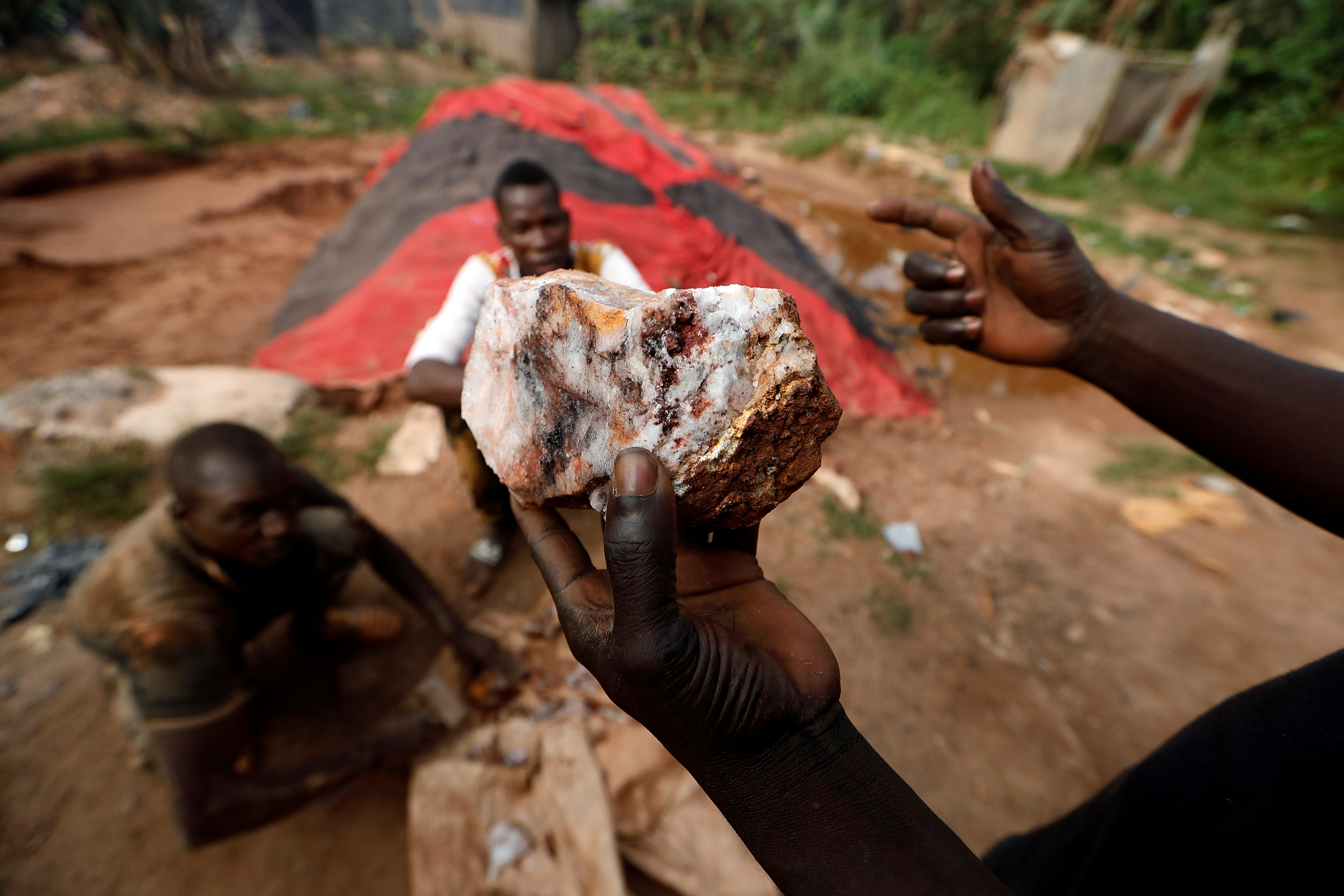 An informal gold miner holds up a rock recovered from inside a gold mine before it is ground down for processing at the site of Nsuaem-Top, Ghana