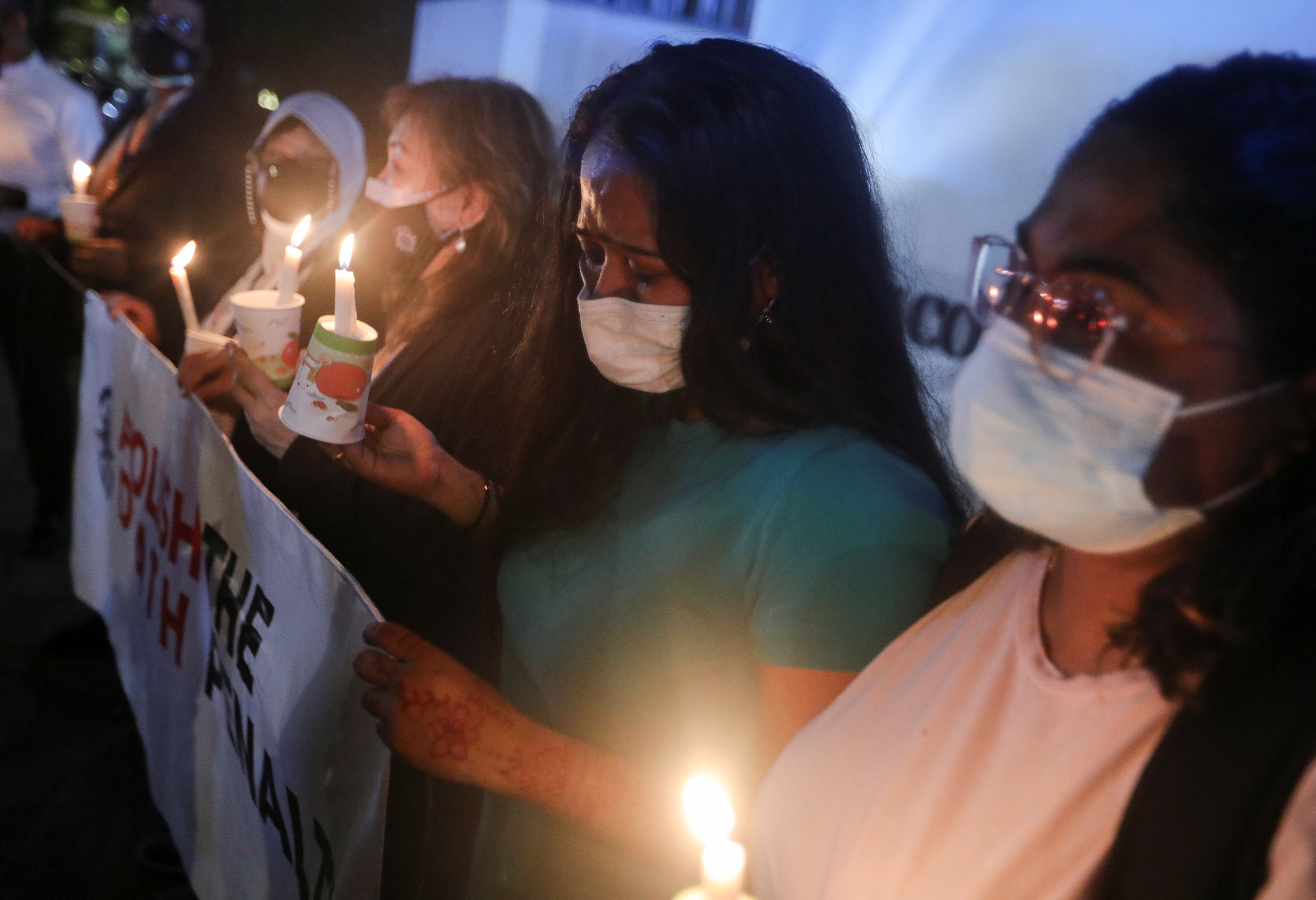 Angelia Pranthaman, sister of Pannir Selvam Pranthaman, a Malaysian drug trafficker facing the death sentence, cries at a vigil for Nagaenthran Dharmalingam, another Malaysian drug trafficker who was hanged last year. She is holding a placard reading 'abolish the death penalty' and other women are holding candles.