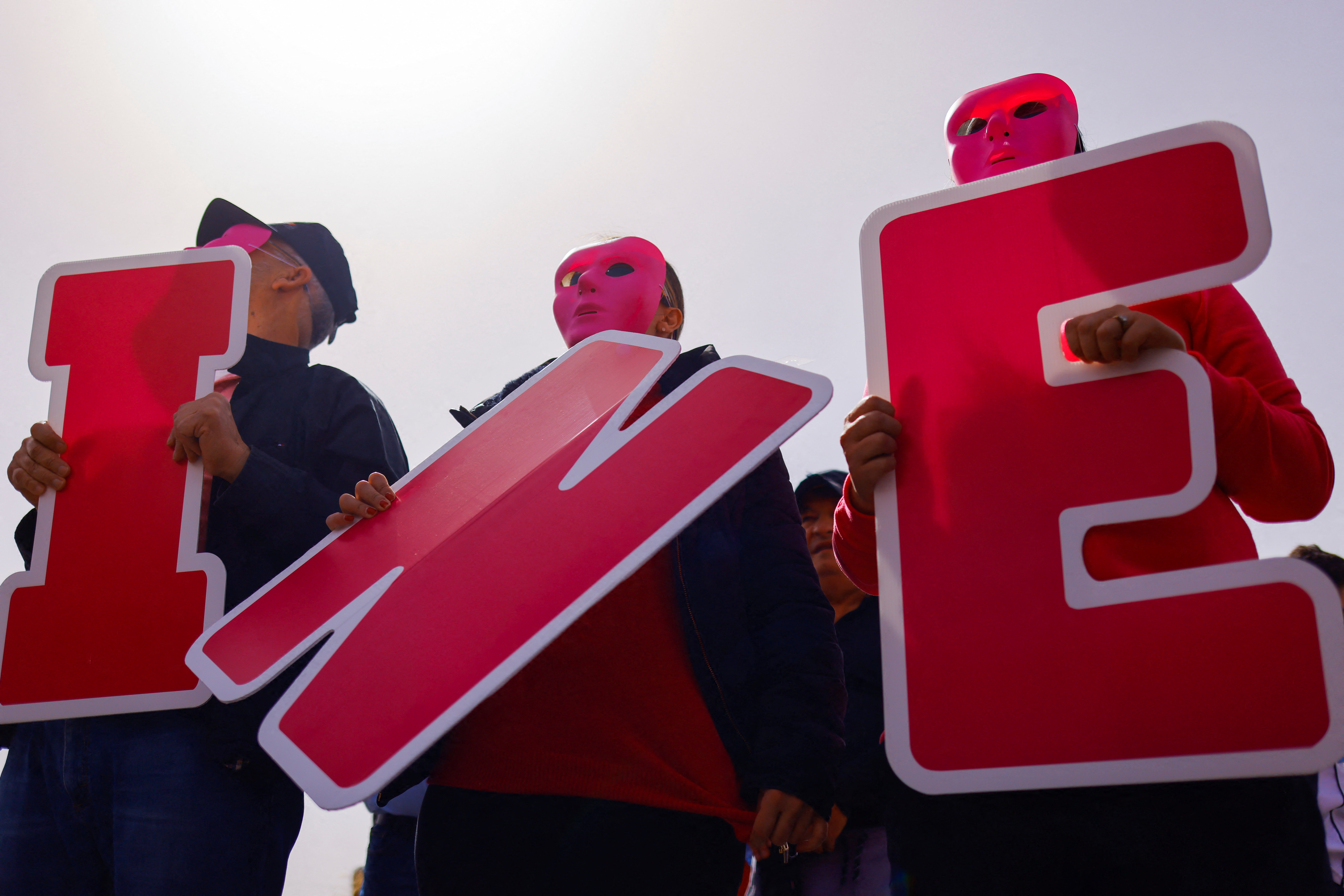 Three demonstrators in February show their support for the National Electoral Institute, by holding up giant letters spelling "INE", after reforms passed that would restrict its budget and power.