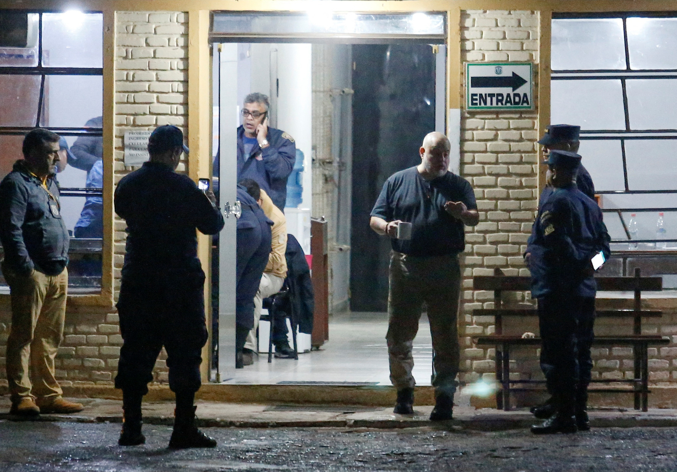 A picture outside a hotel shows Paraguayo Cubas talking to police officers . Someone can be seen inside the building as well