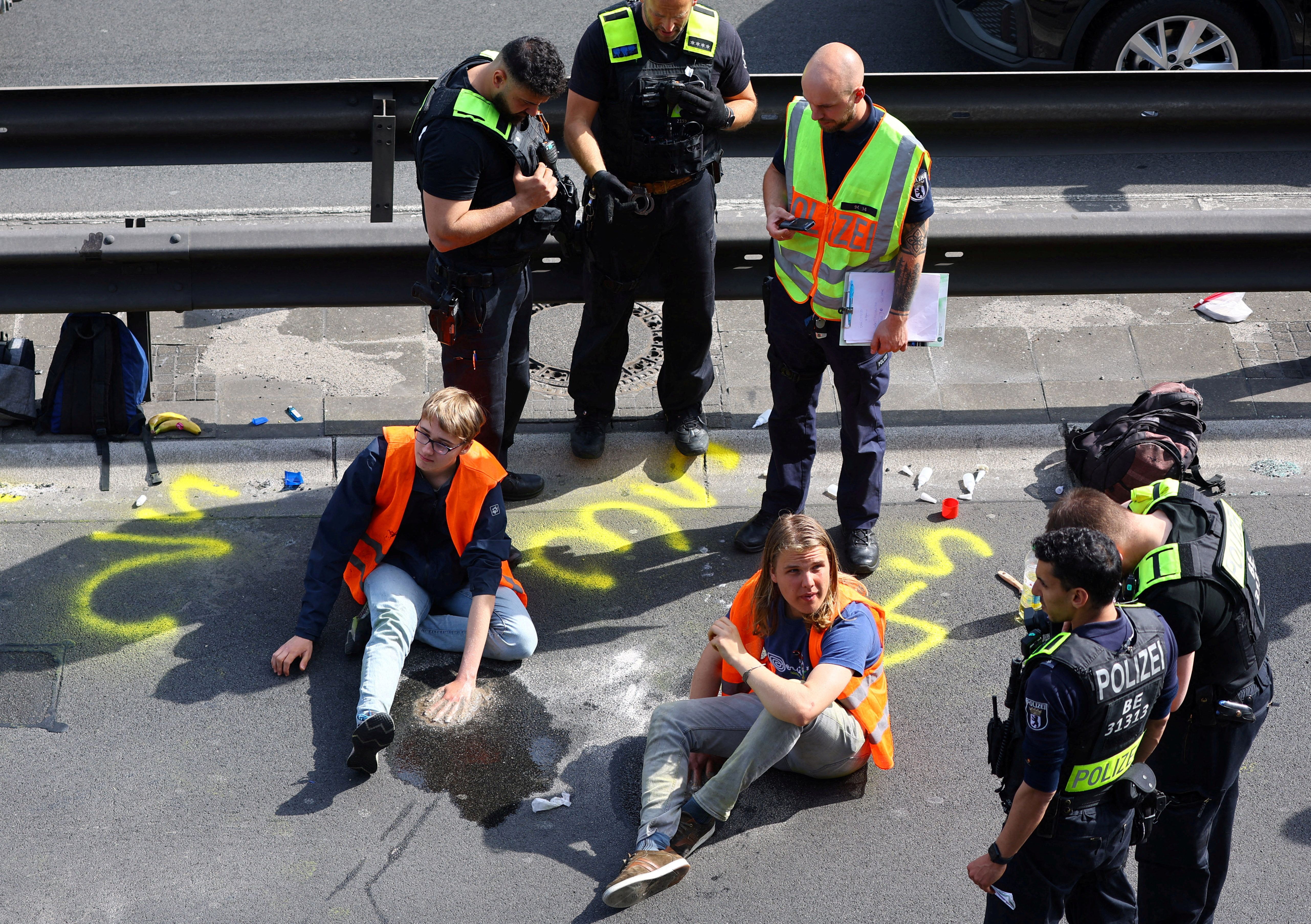 Police surround activists of the "Letzte Generation" (Last Generation) after they glued their hands on asphalt, while blocking the central highway A100 to protest for climate councils, a speed limit on highways as well as for affordable public transport, in Berlin, Germany, May 22, 2023.