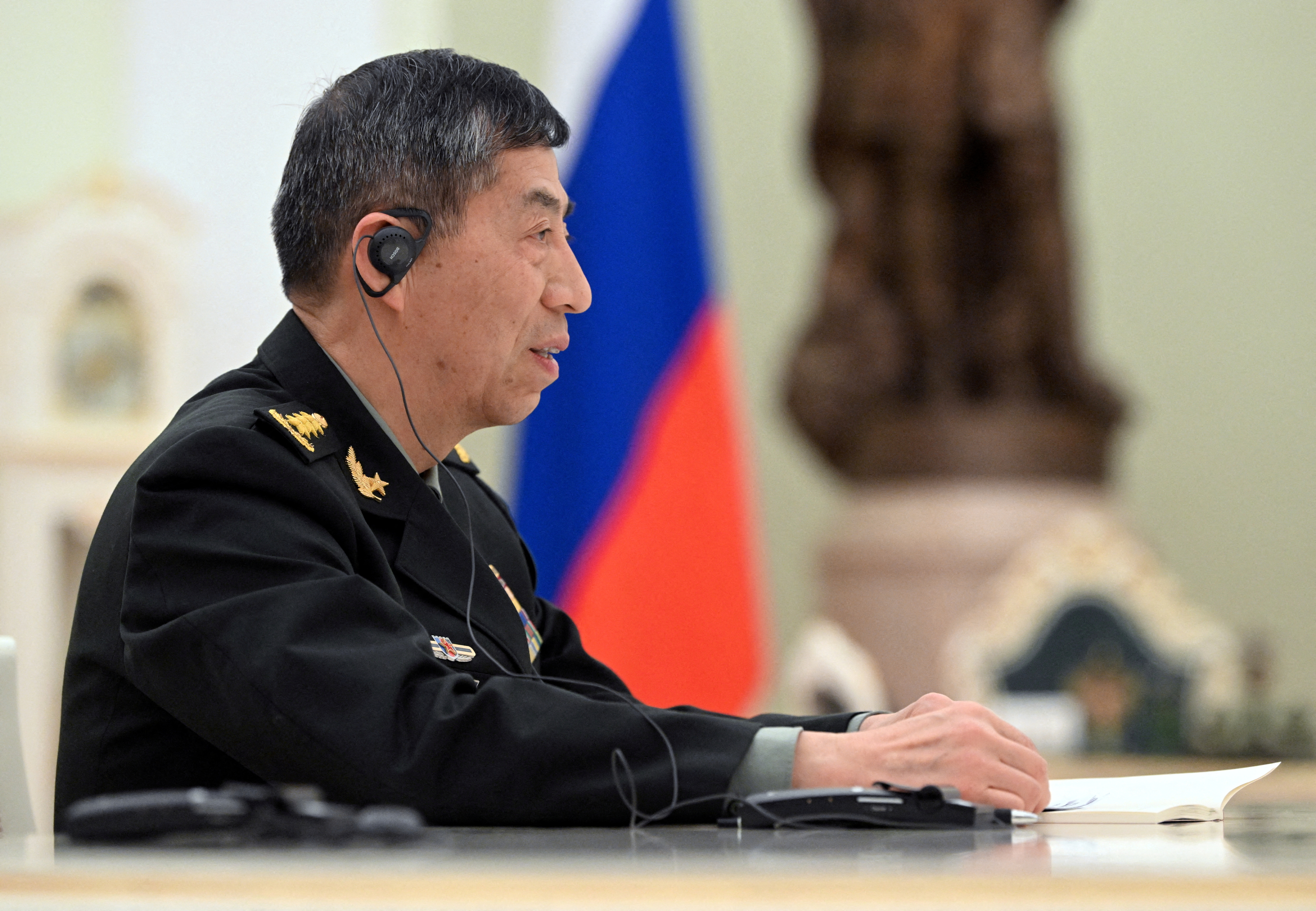 Chinese Defence Minister Li Shangfu at a meeting in Russia. He is wearing a military uniform and headphones for translation.