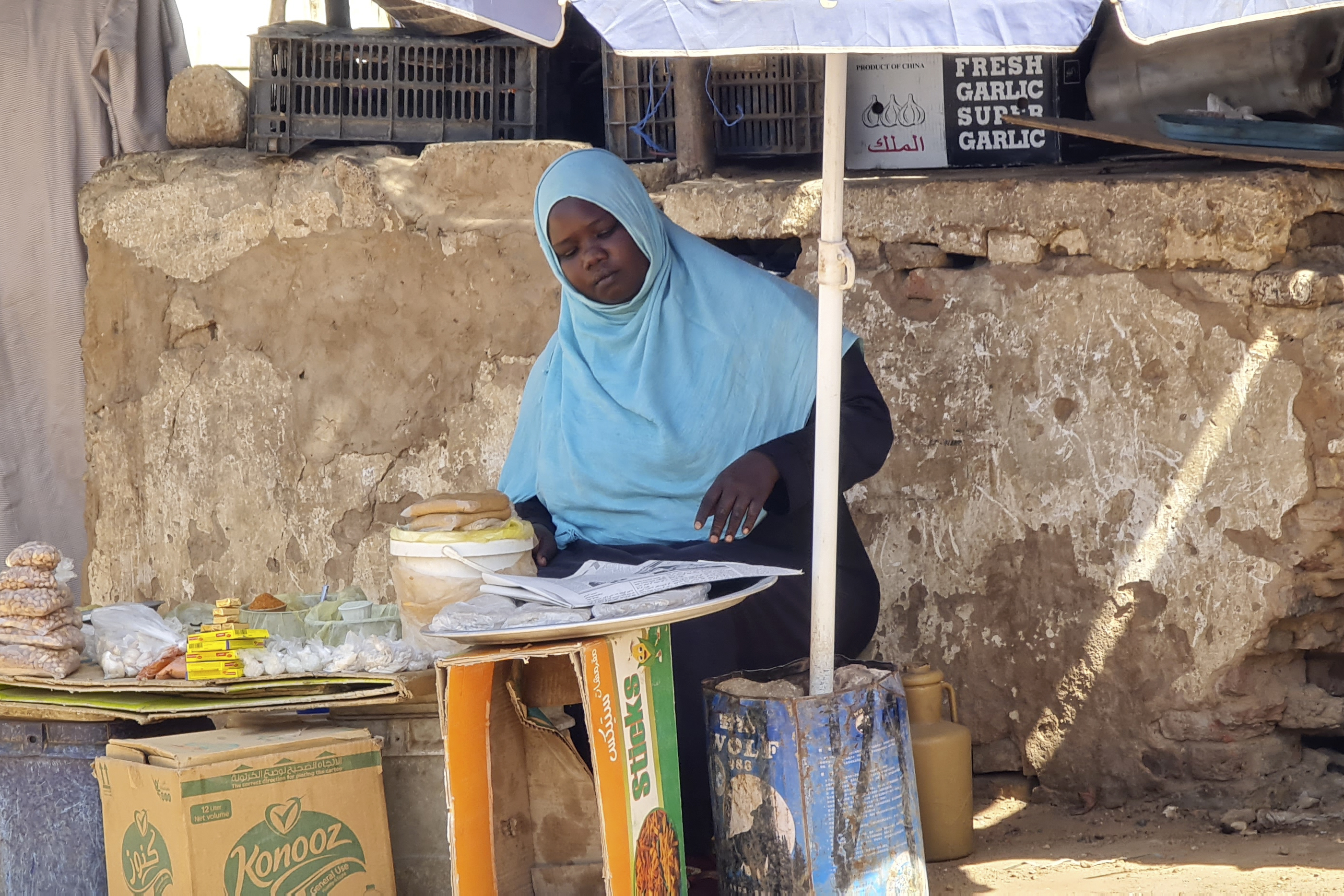 A woman sells foodstuffs at a stall on a market street in southern Khartoum