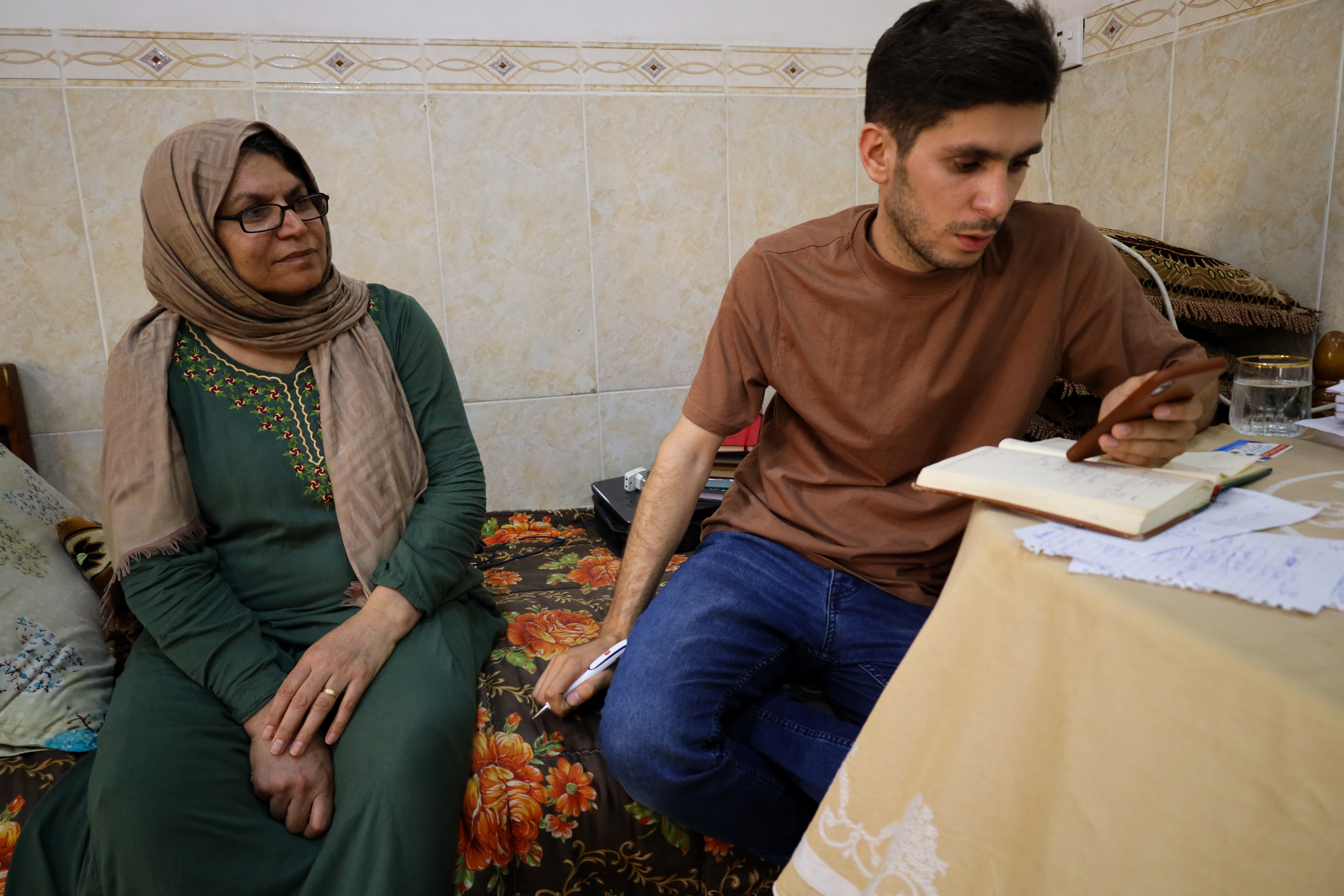 A photo of Mumen and his mother at home in Erbil, looking over April's expenses.