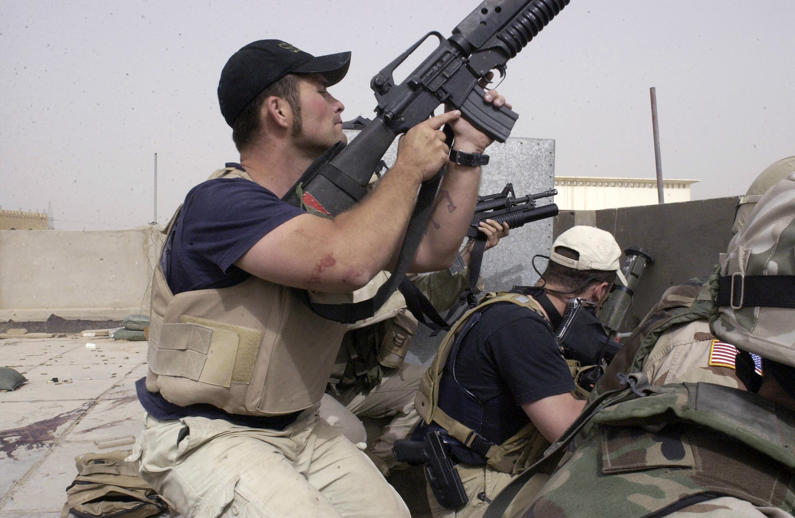 In this April 4, 2004 file photo, plainclothes contractors working for Blackwater USA take part in a firefight as Iraqi demonstrators loyal to Muqtada al-Sadr attempt to advance on a facility being defended by US and Spanish soldiers in the Iraqi city of Najaf.